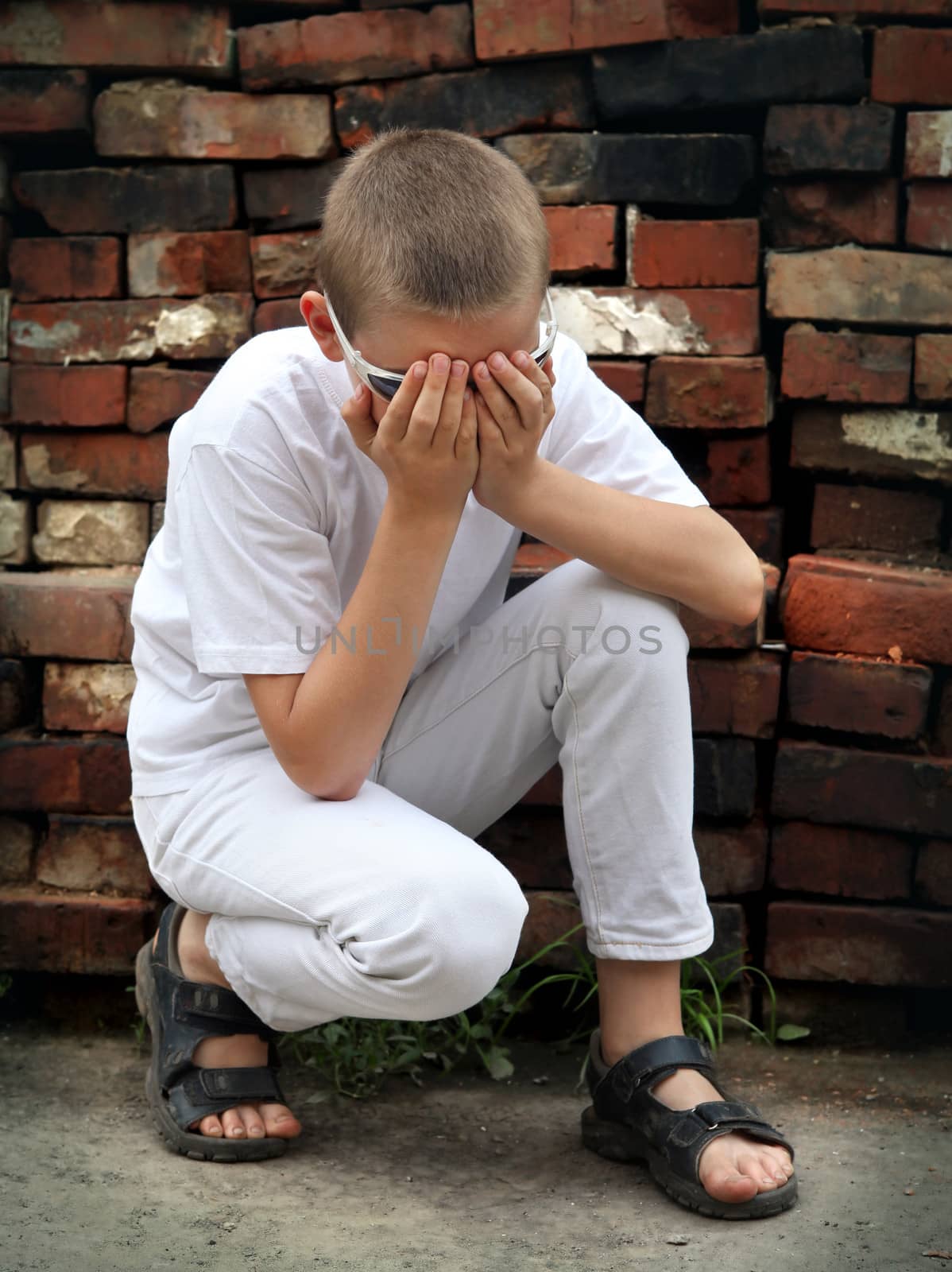 Sad Boy sit near the old brick wall
