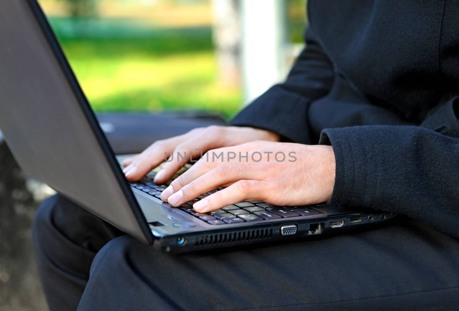 Person working on Laptop at the Autumn Park. Hands Closeup