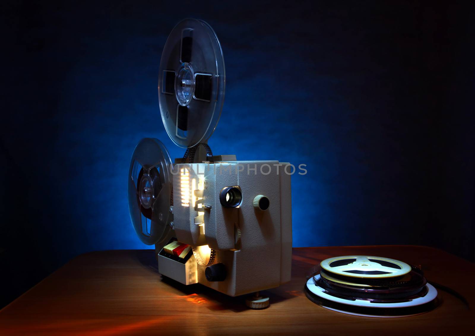 Old 8mm film projector in dusk beside a stack of film reels