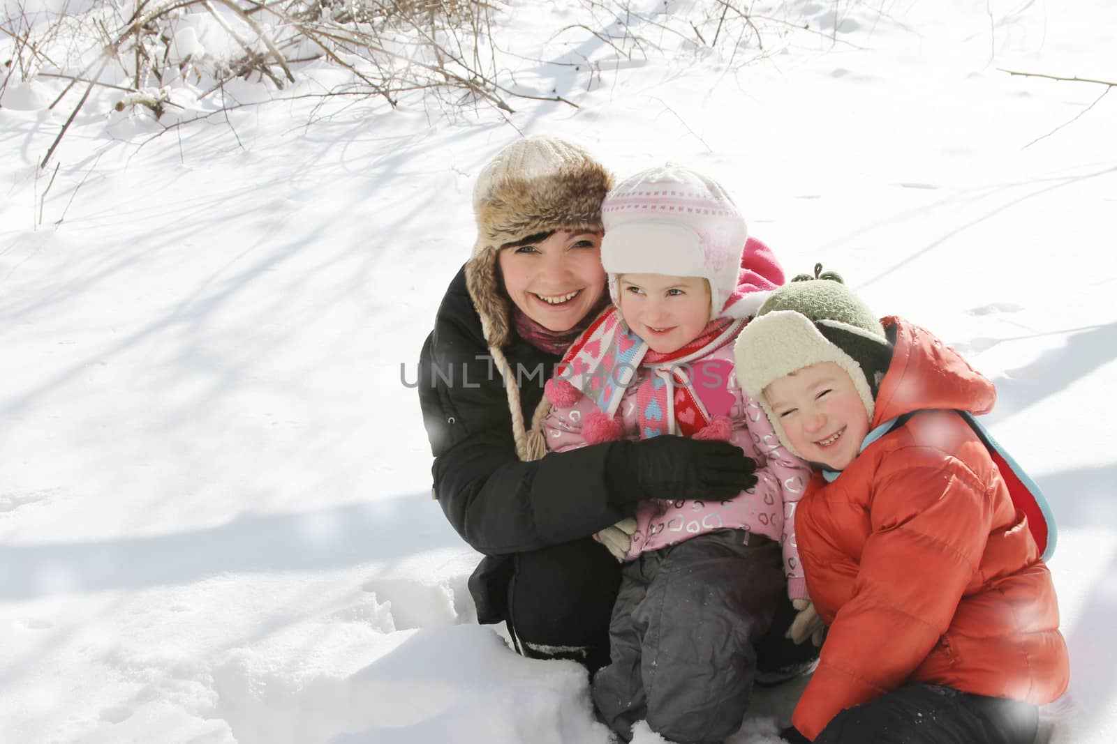 Happy mother with two children lying in snow with copy space