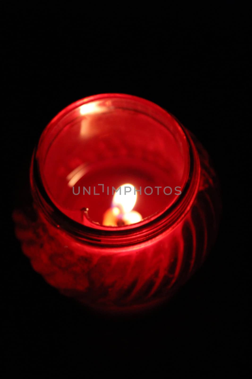 dimly burning church candle on glass candlestick in church