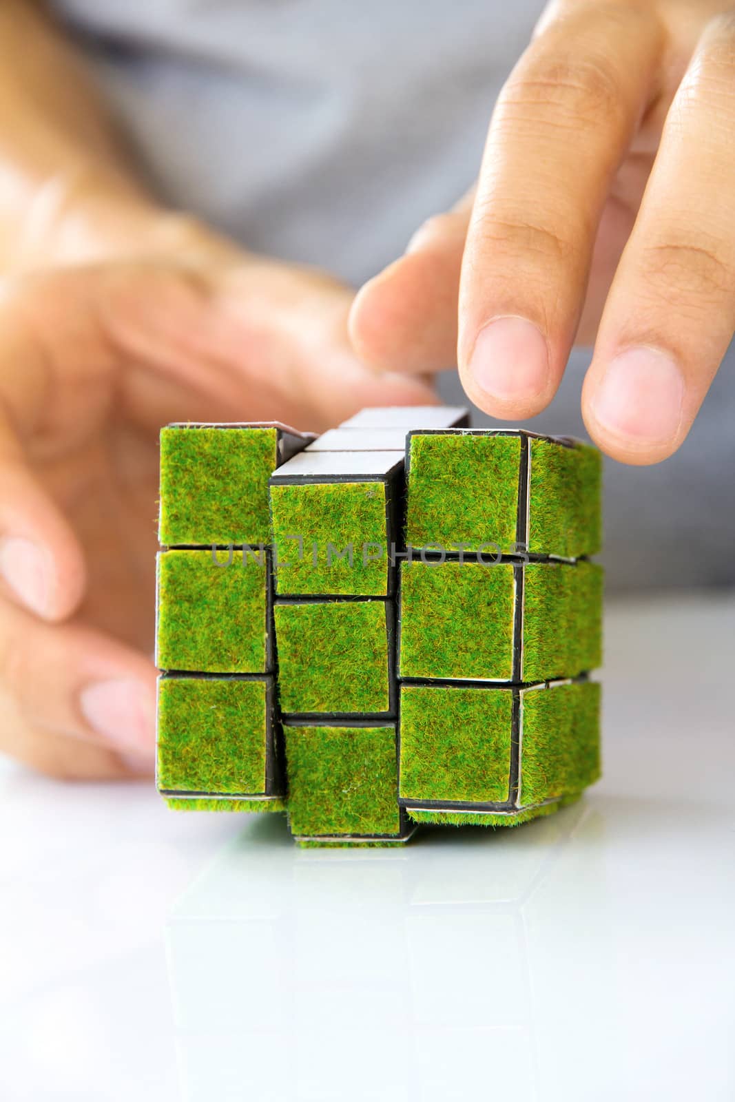 hand holding green rubik's cube concept by ponsulak