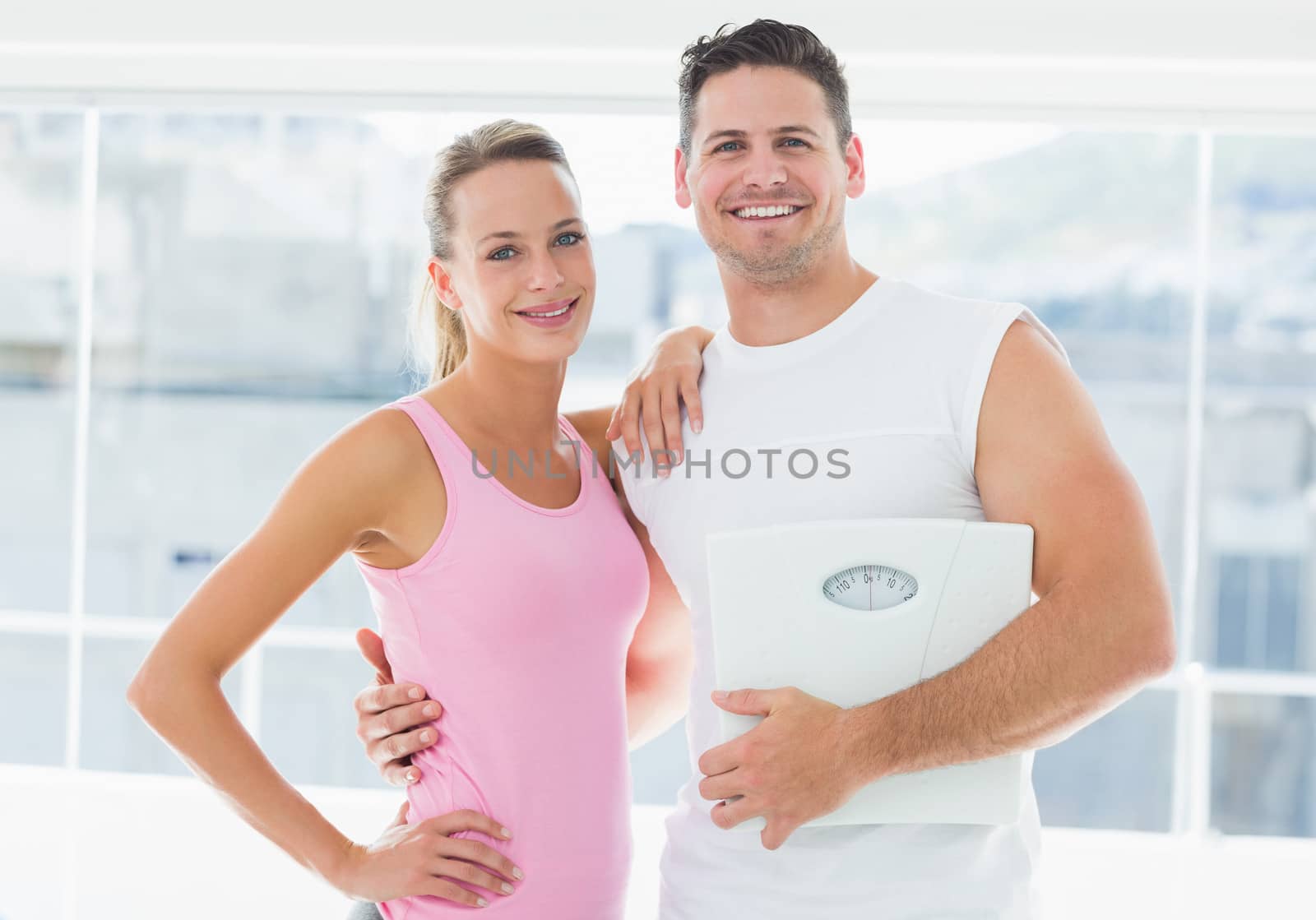 Portrait of a fit couple holding weighing scale by Wavebreakmedia