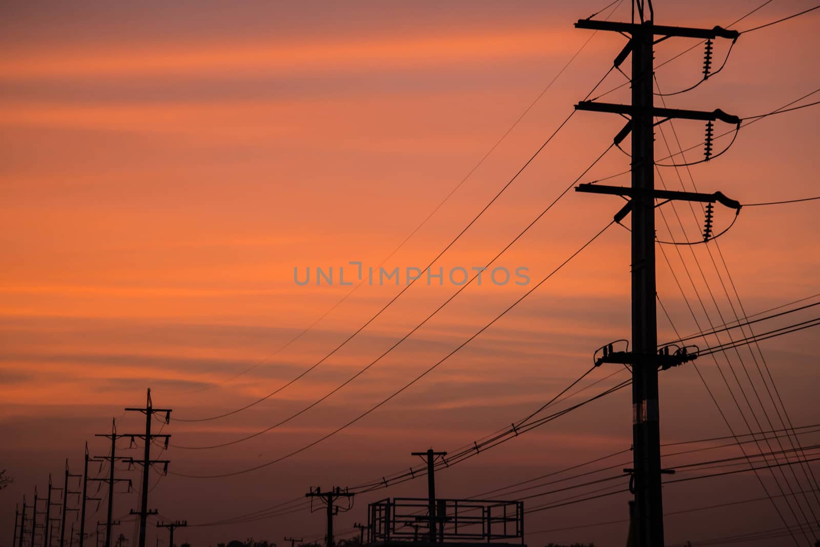 Electricity cable communication towers on sunset stretching across the river.