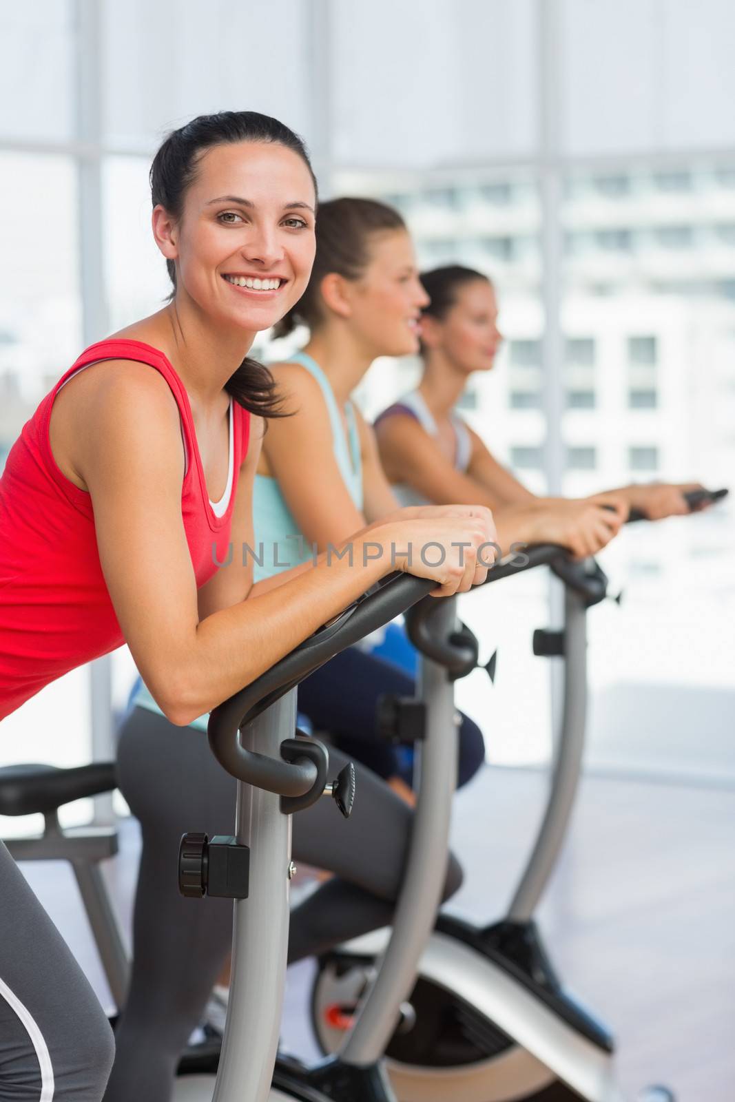 Side view portrait of fit young people working out at spinning class in gym
