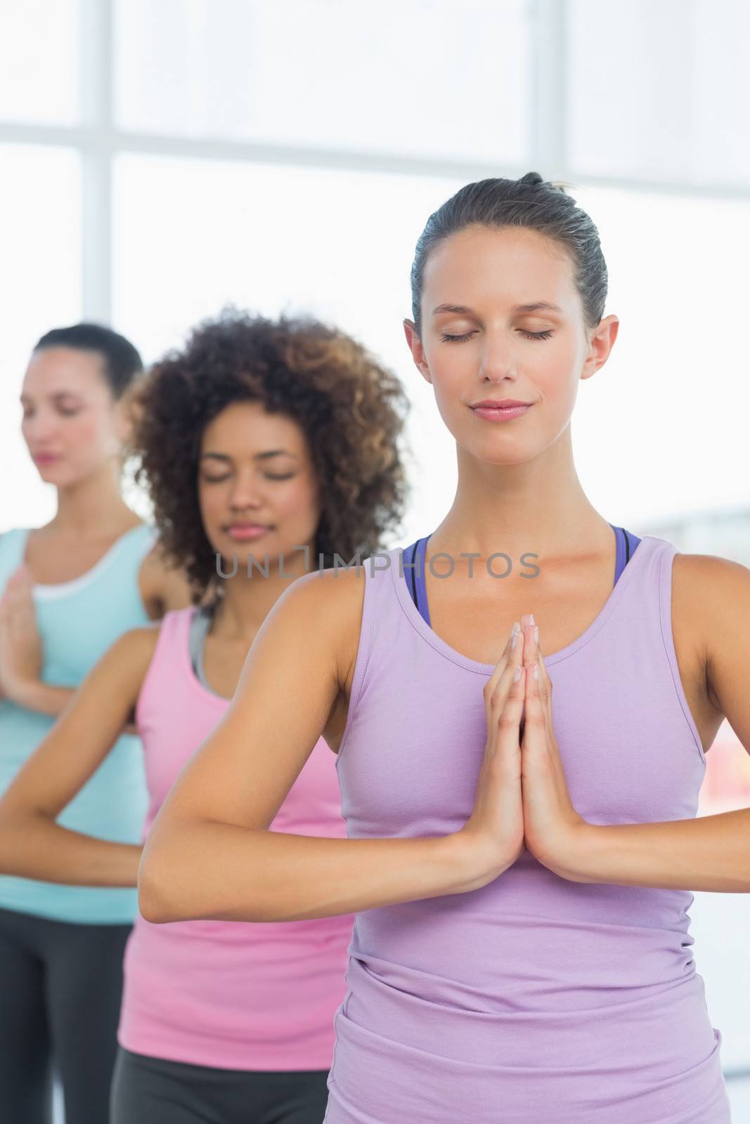 Women in meditation pose with eyes closed at fitness studio by Wavebreakmedia
