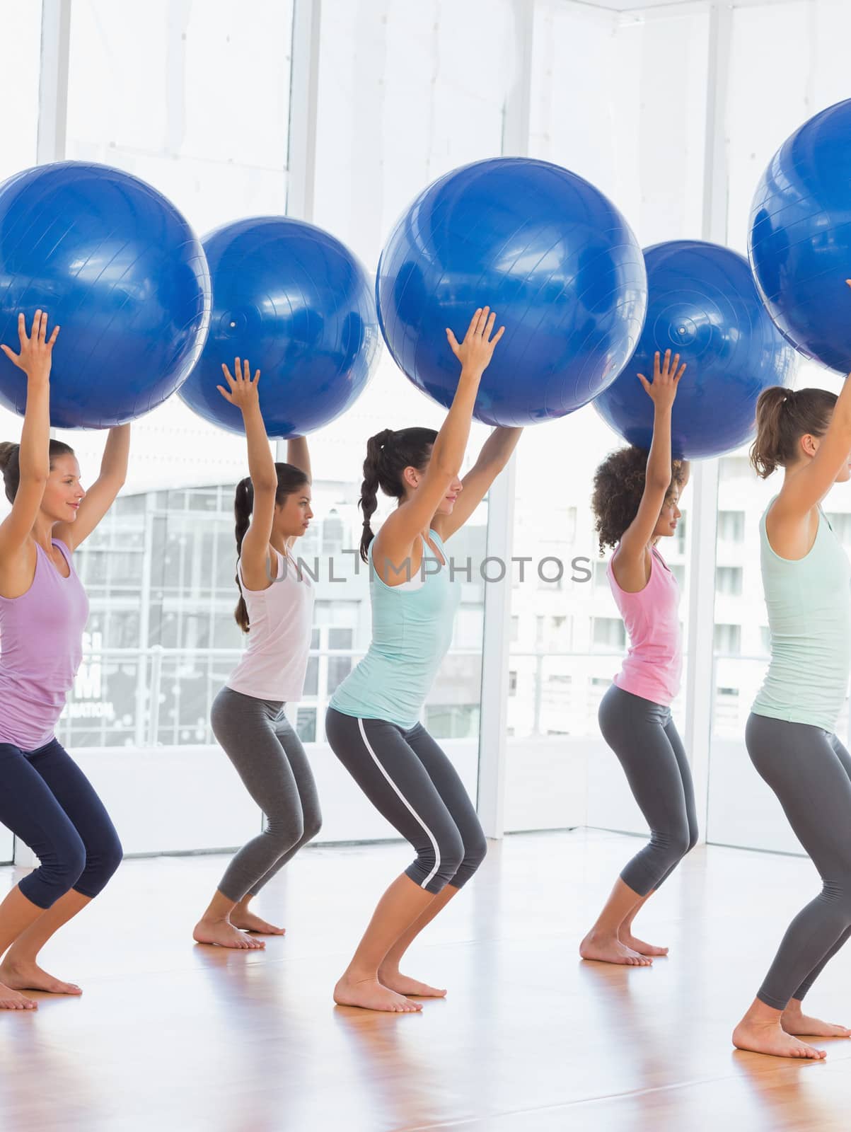 Fit women holding blue fitness balls in exercise room by Wavebreakmedia