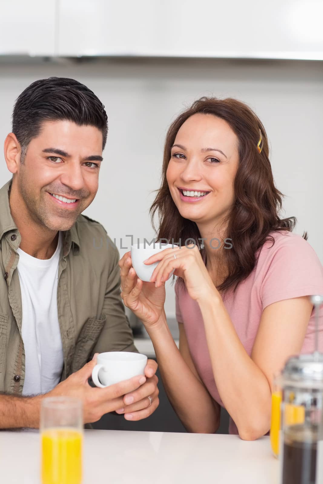 Portrait of a happy loving couple with coffee cup in the kitchen at home