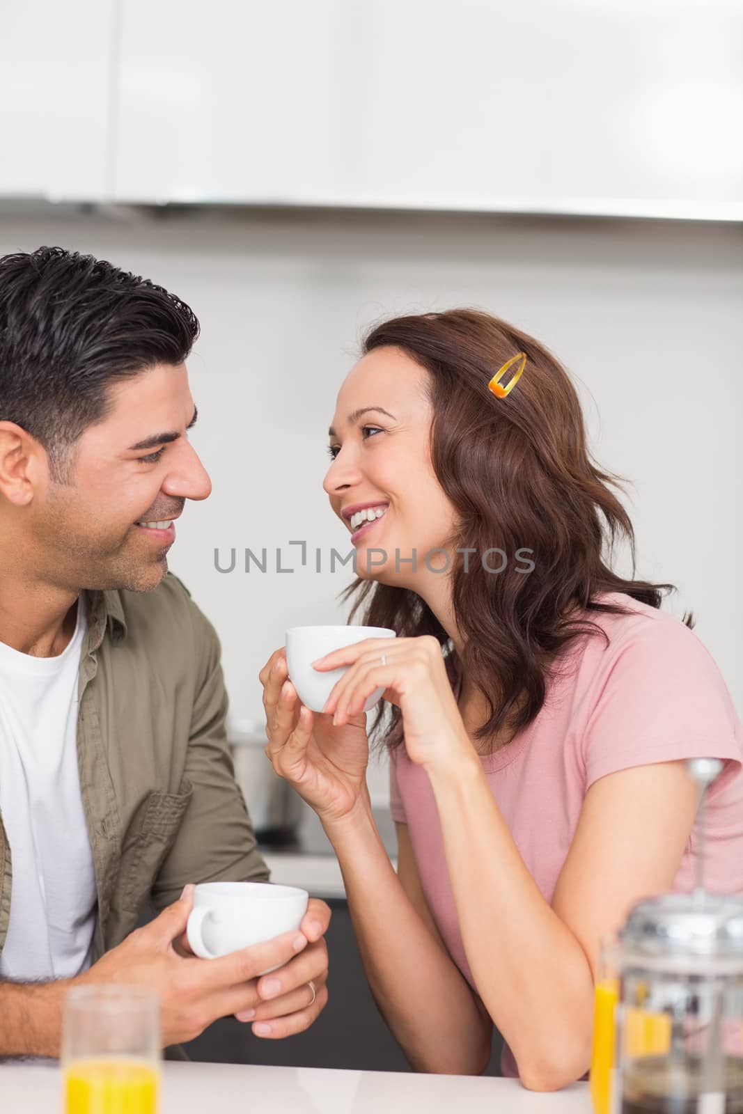 Happy loving couple with coffee cup in the kitchen at home