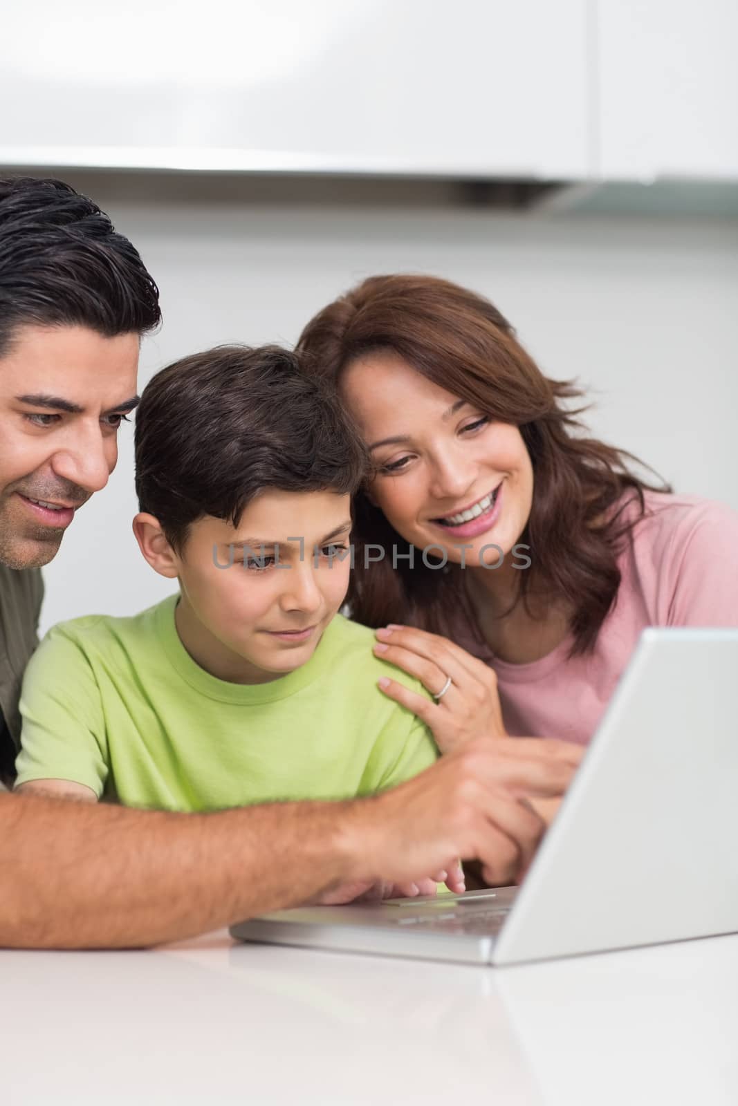 Smiling couple with young son using laptop at home