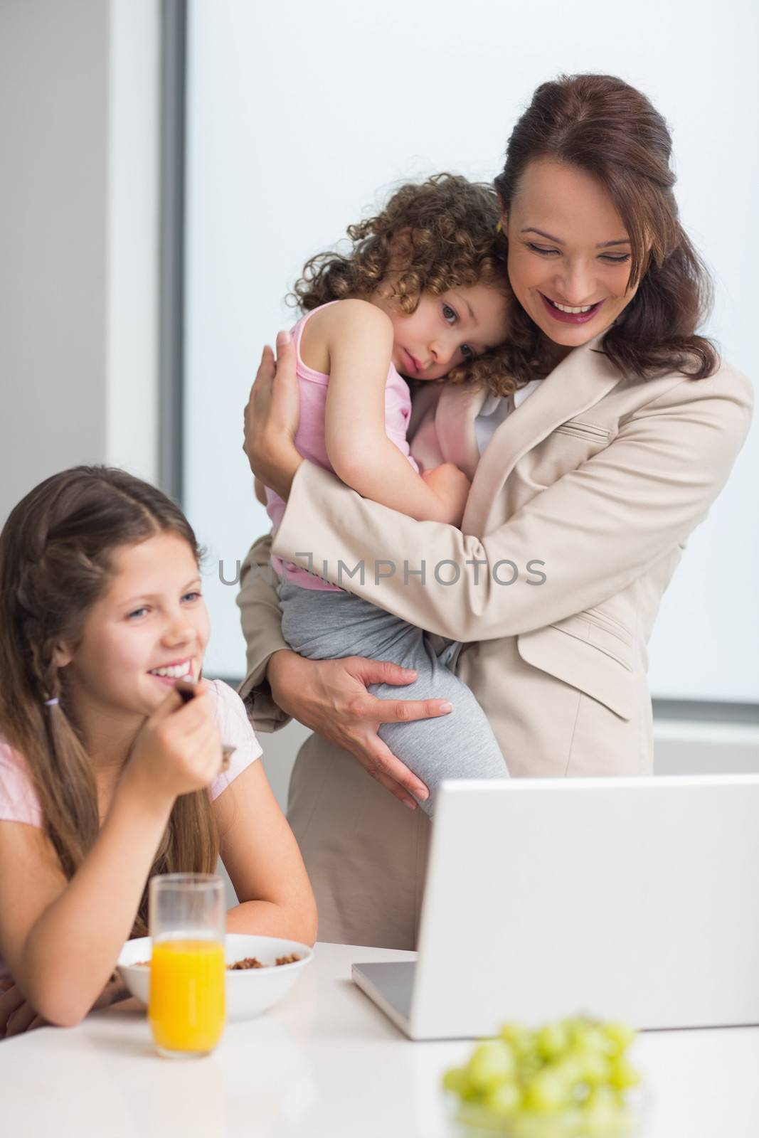 Well dressed mother with daughters and laptop in kitchen by Wavebreakmedia