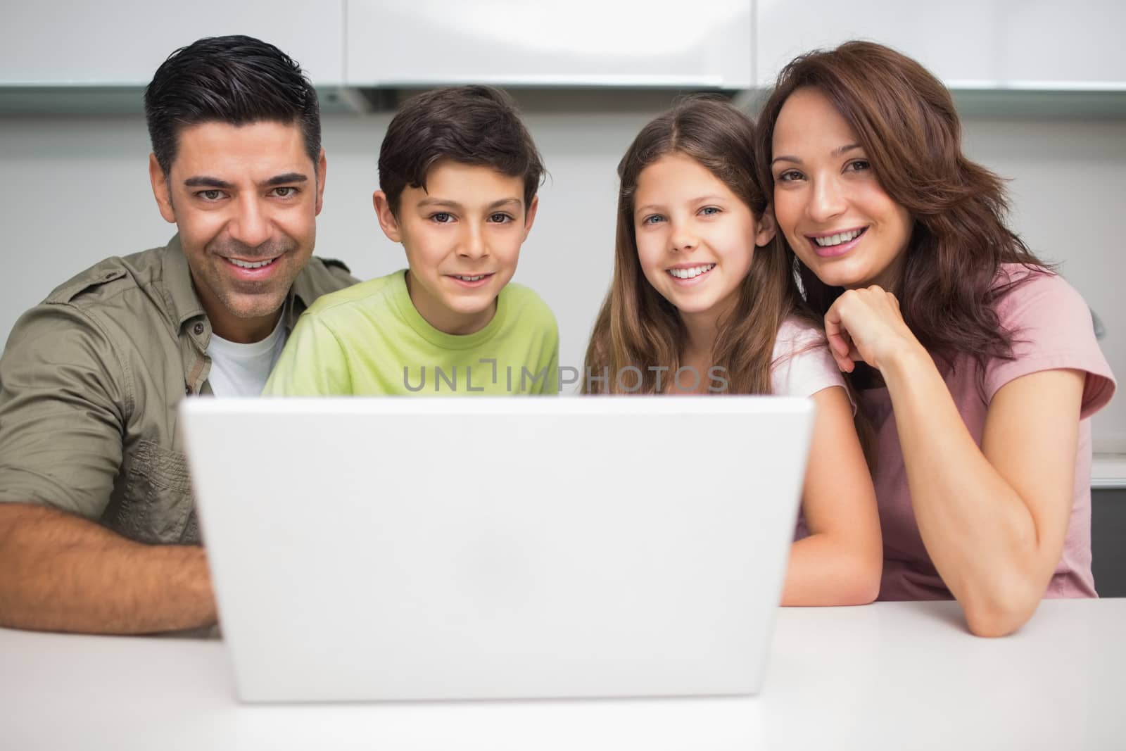 Portrait of a smiling couple with young kids using laptop at home