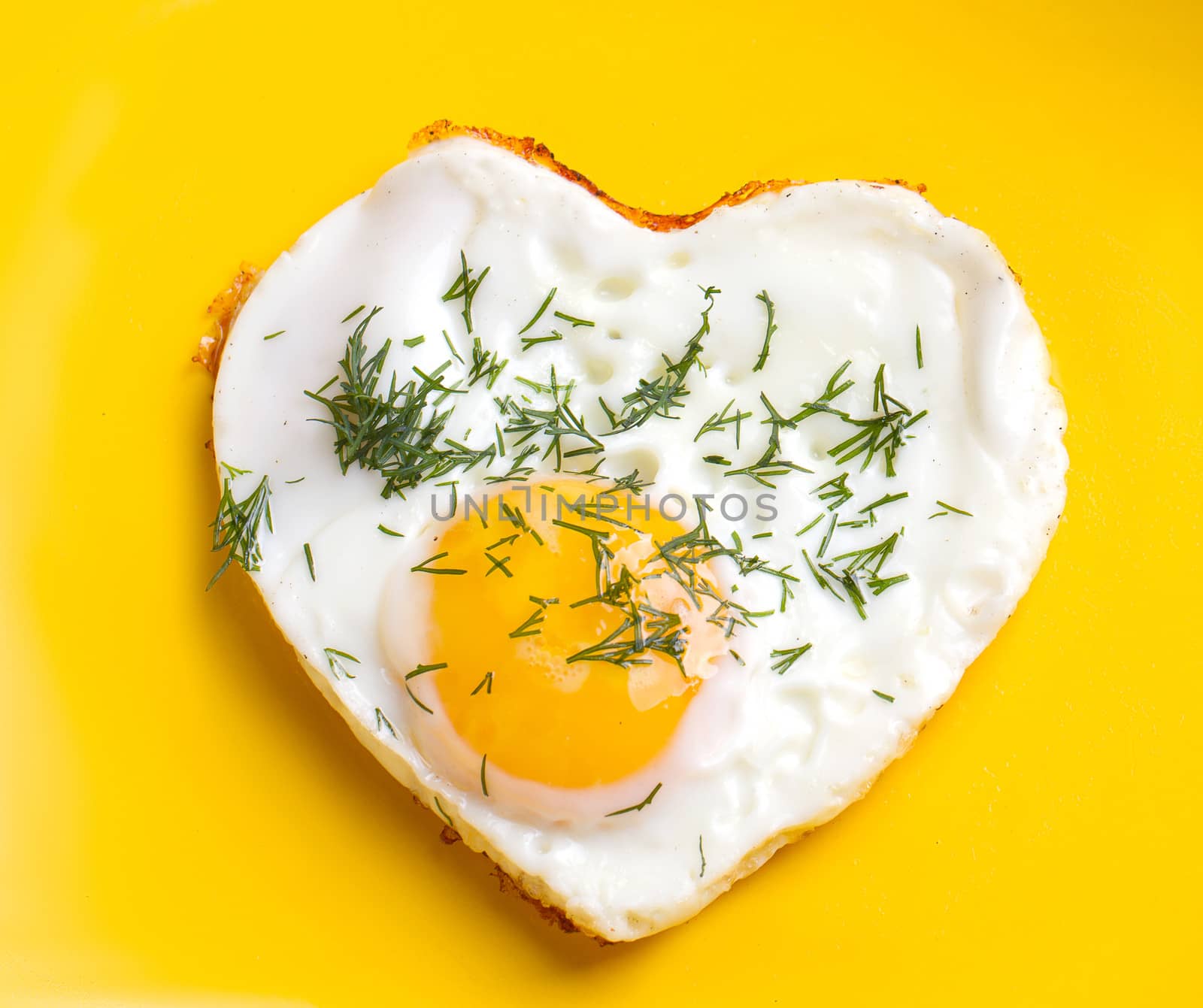 Breakfast. Fried eggs in a heart shape with dill