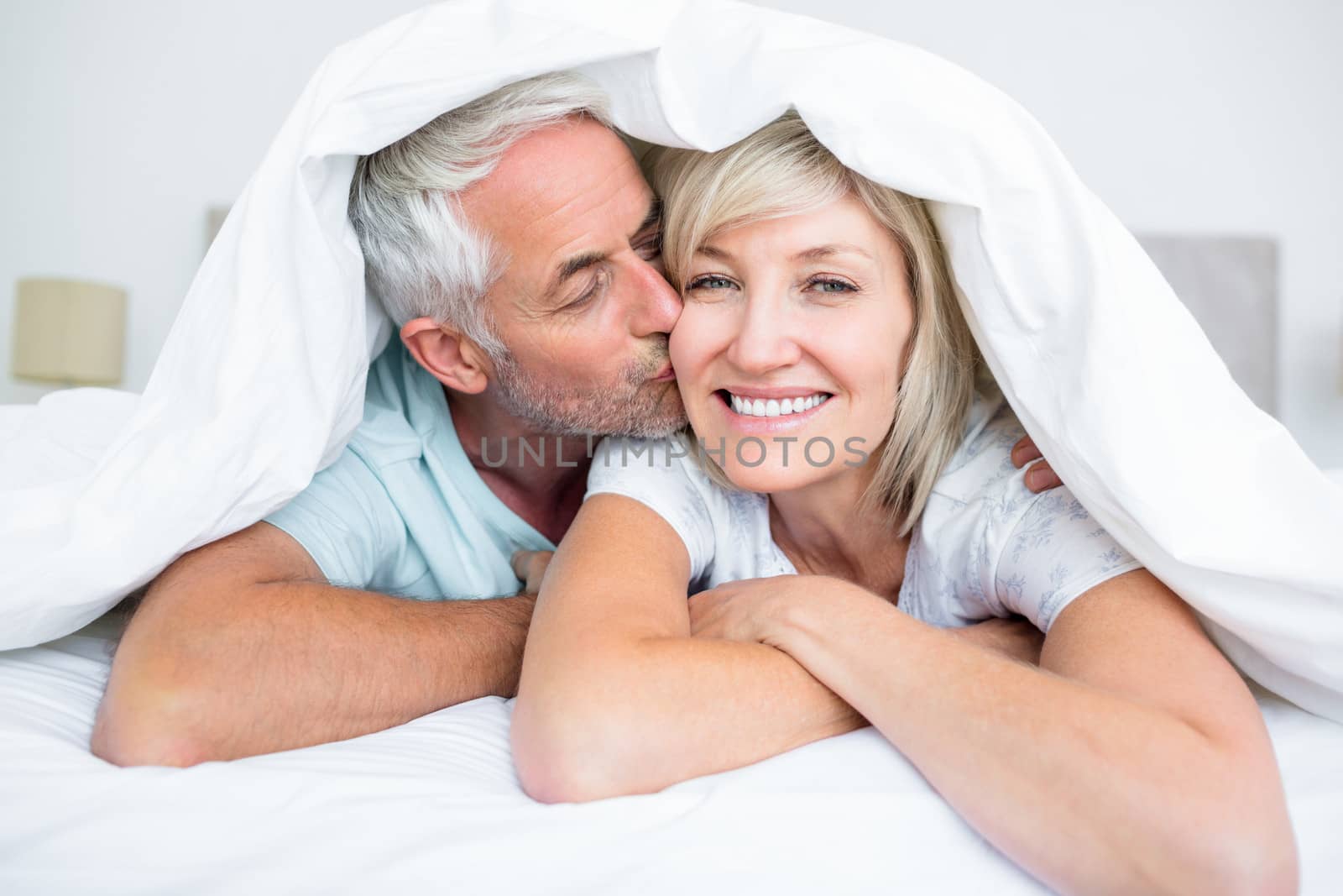 Closeup of mature man kissing womans cheek in bed by Wavebreakmedia