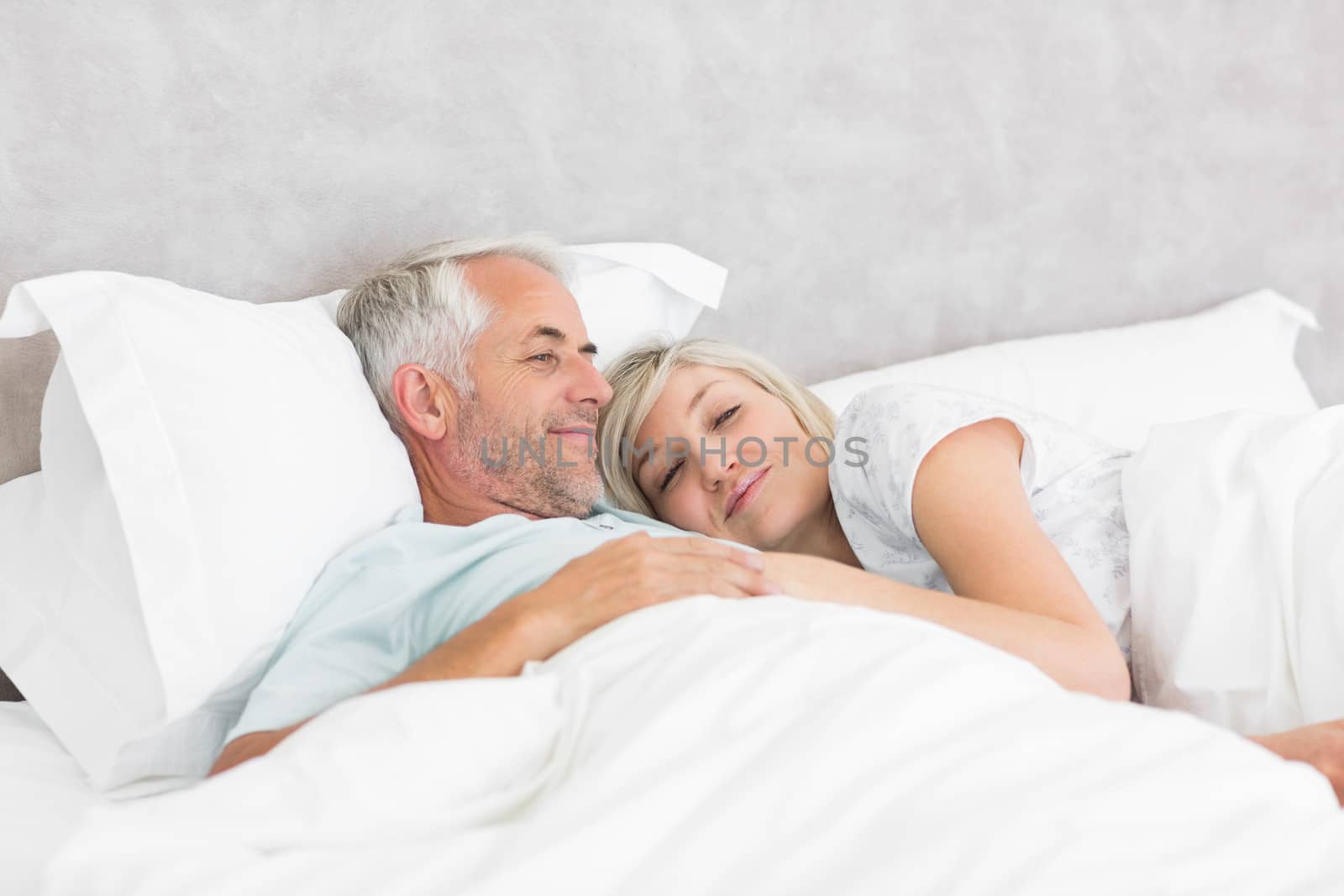 Loving mature man and woman lying in bed by Wavebreakmedia