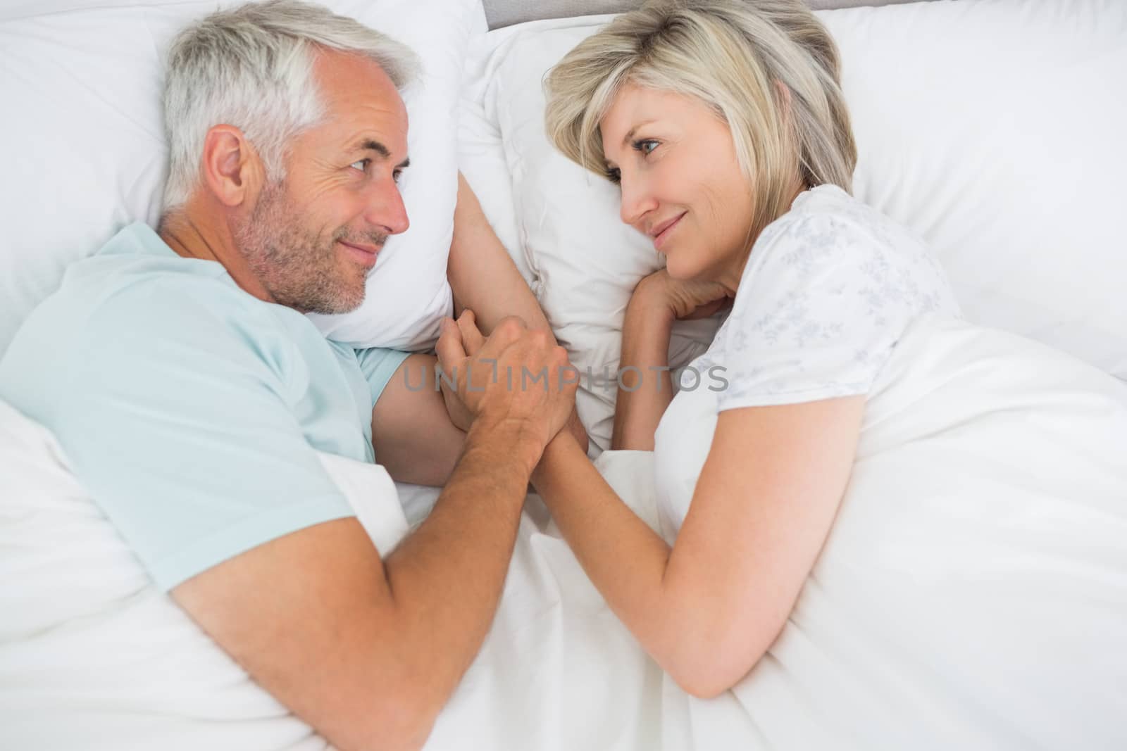 Loving mature man and woman lying in bed at the home