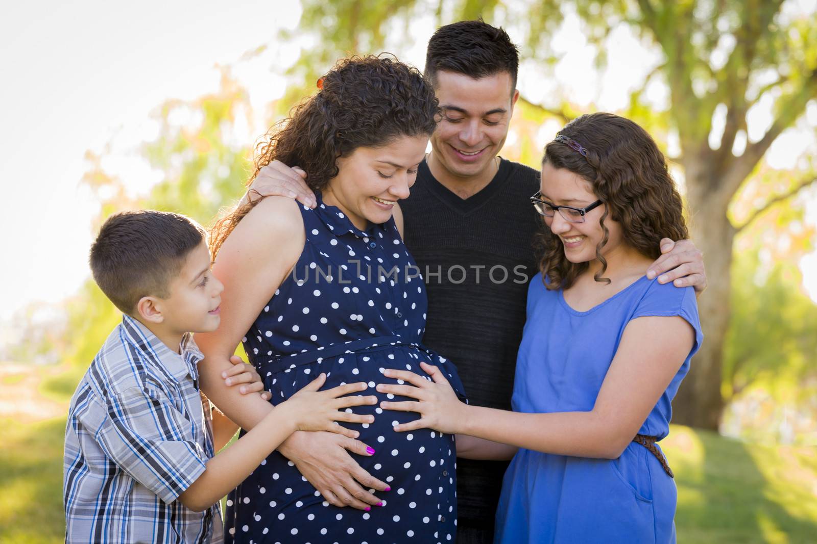 Hispanic Family Hands on Pregnant Mother Tummy Feeling Baby Kick Outdoors At The Park.