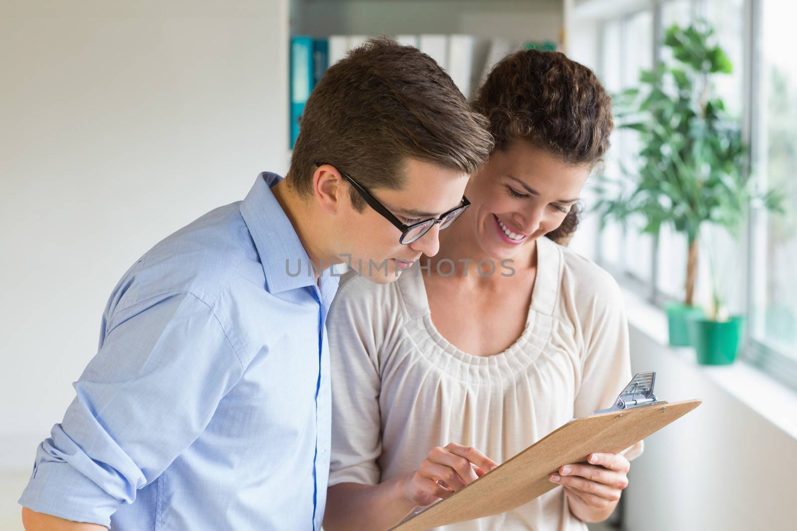 Young business people discussing over clipboard in office