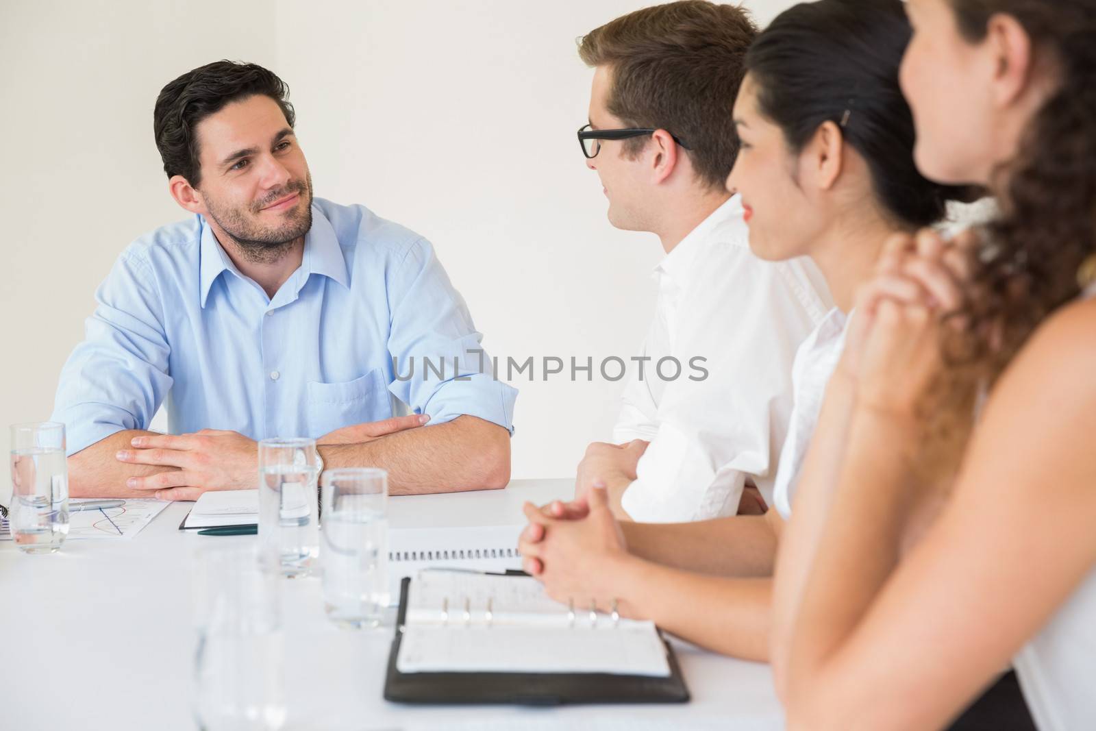 Confident young businessman discussing with colleagues in meeting at office