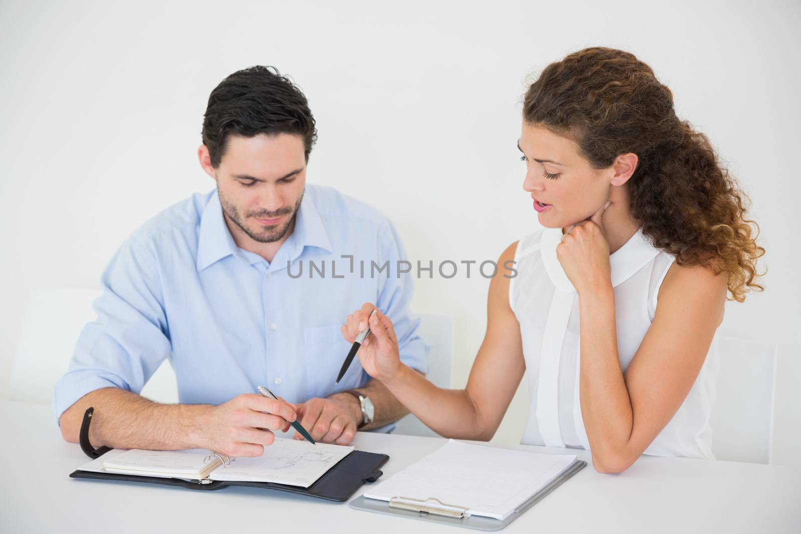 Businessman with female colleague discussing together at desk in office