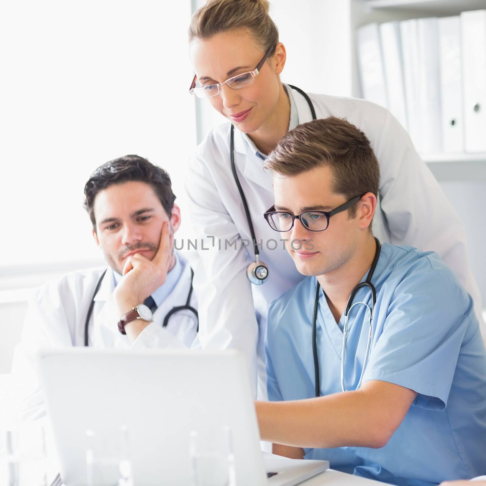 Doctors and male nurse working on laptop in hospital