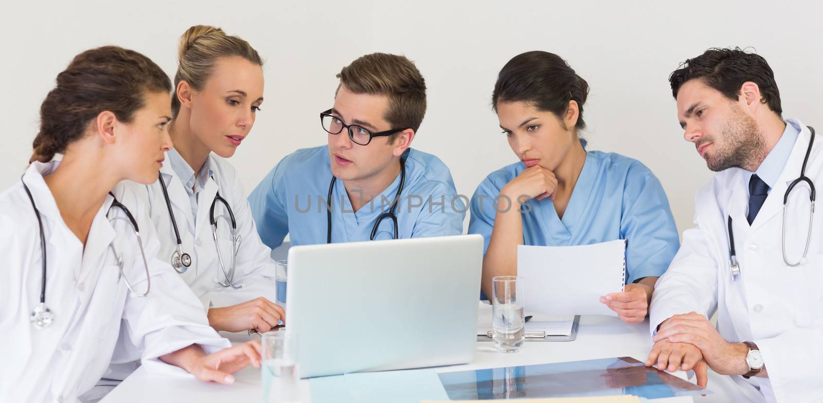 Medical team discussing over laptop in hospital