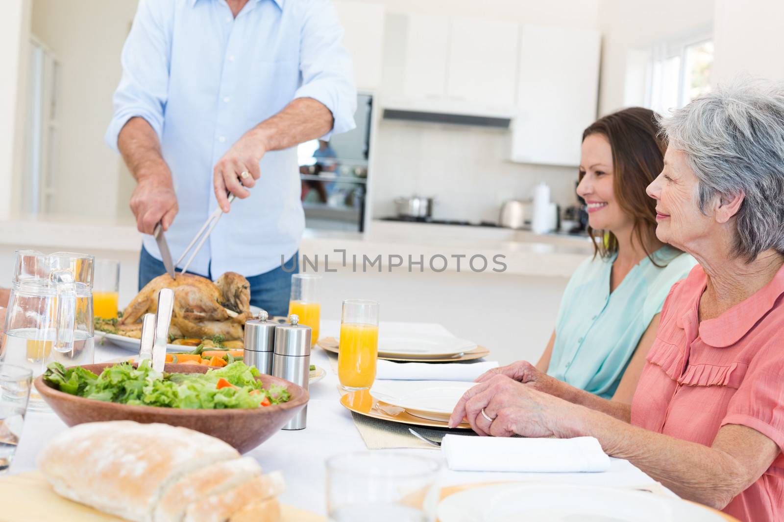 Senior man serving food to family at dining table