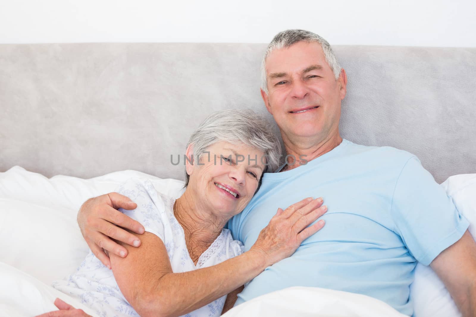 Portrait of senior man embracing woman in bed at home