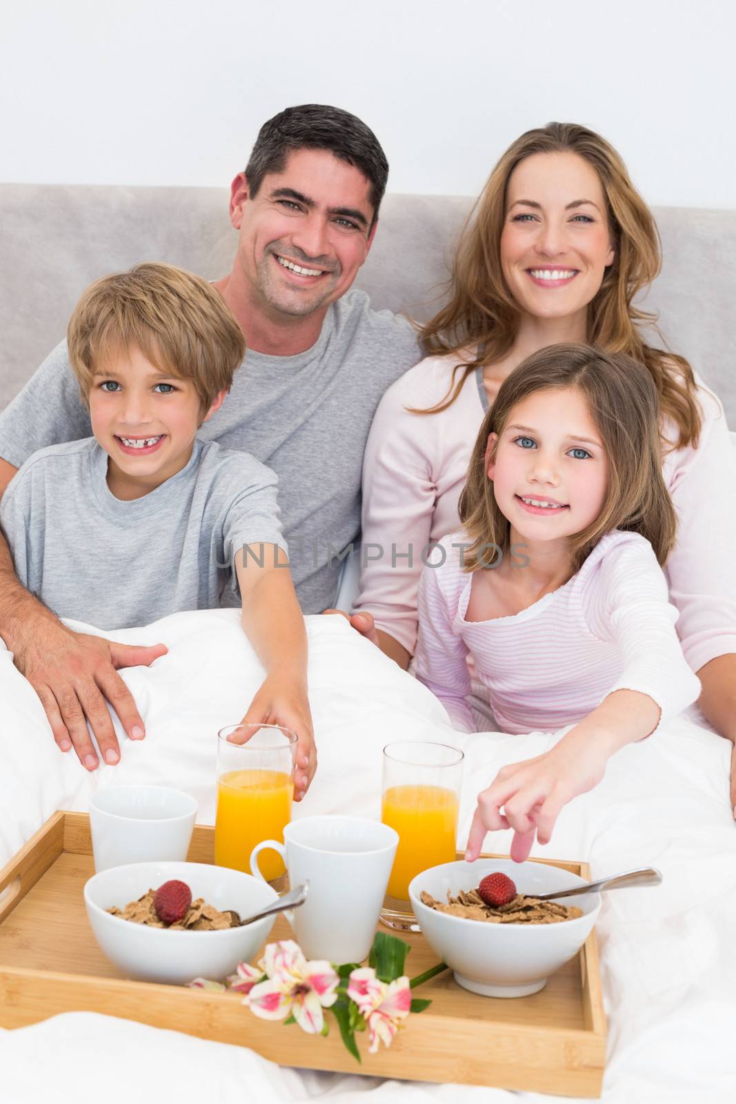 Portrait of happy family having breakfast in bed