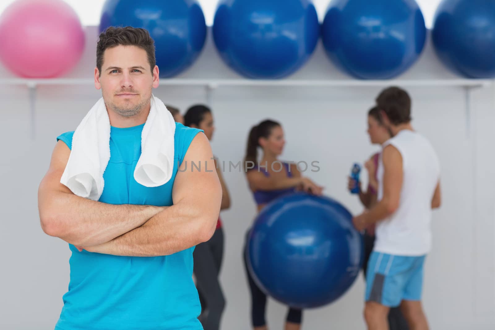 Portrait of a fit young man with friends in background at fitness studio