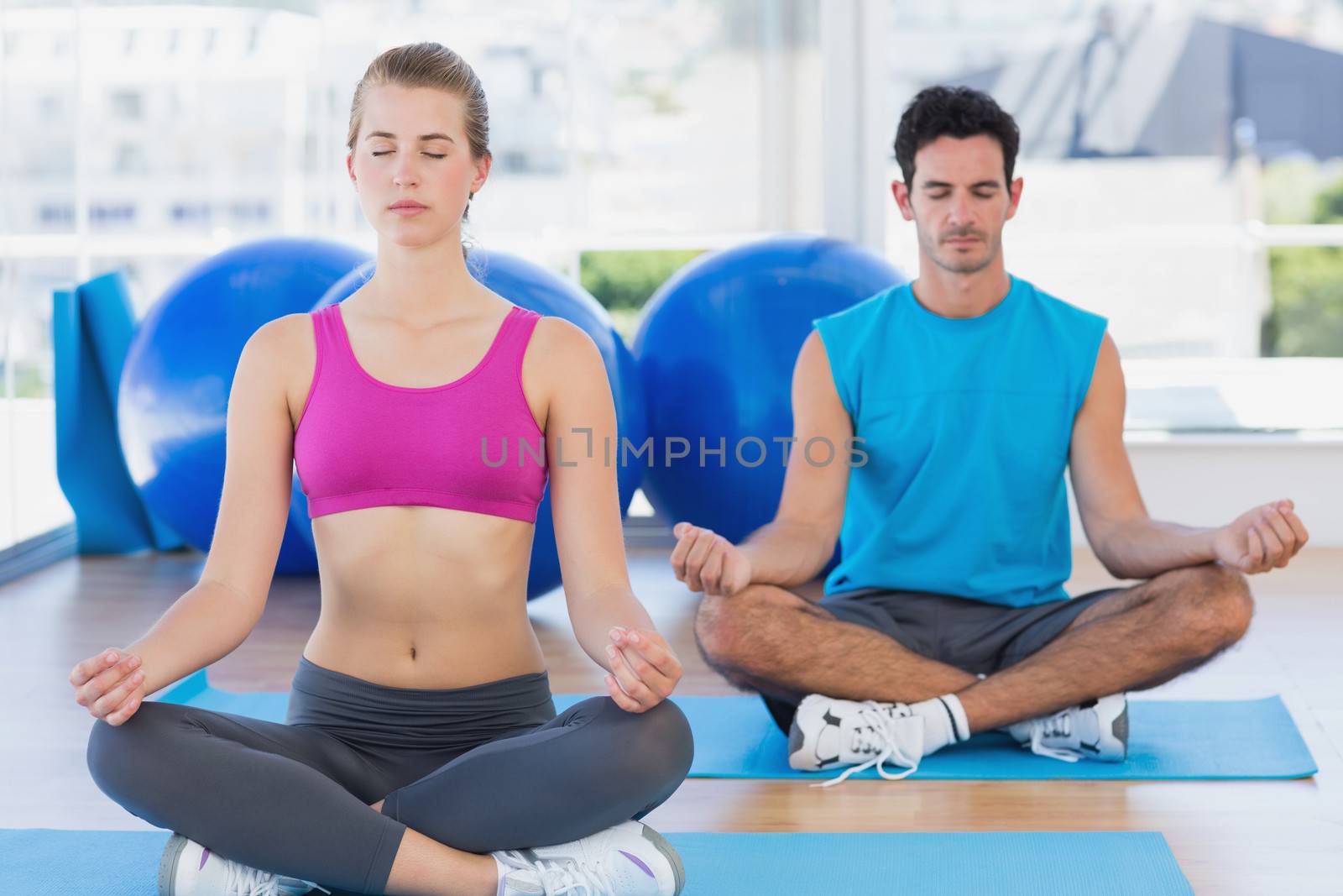 Couple sitting in lotus posture and eyes closed at fitness studio by Wavebreakmedia
