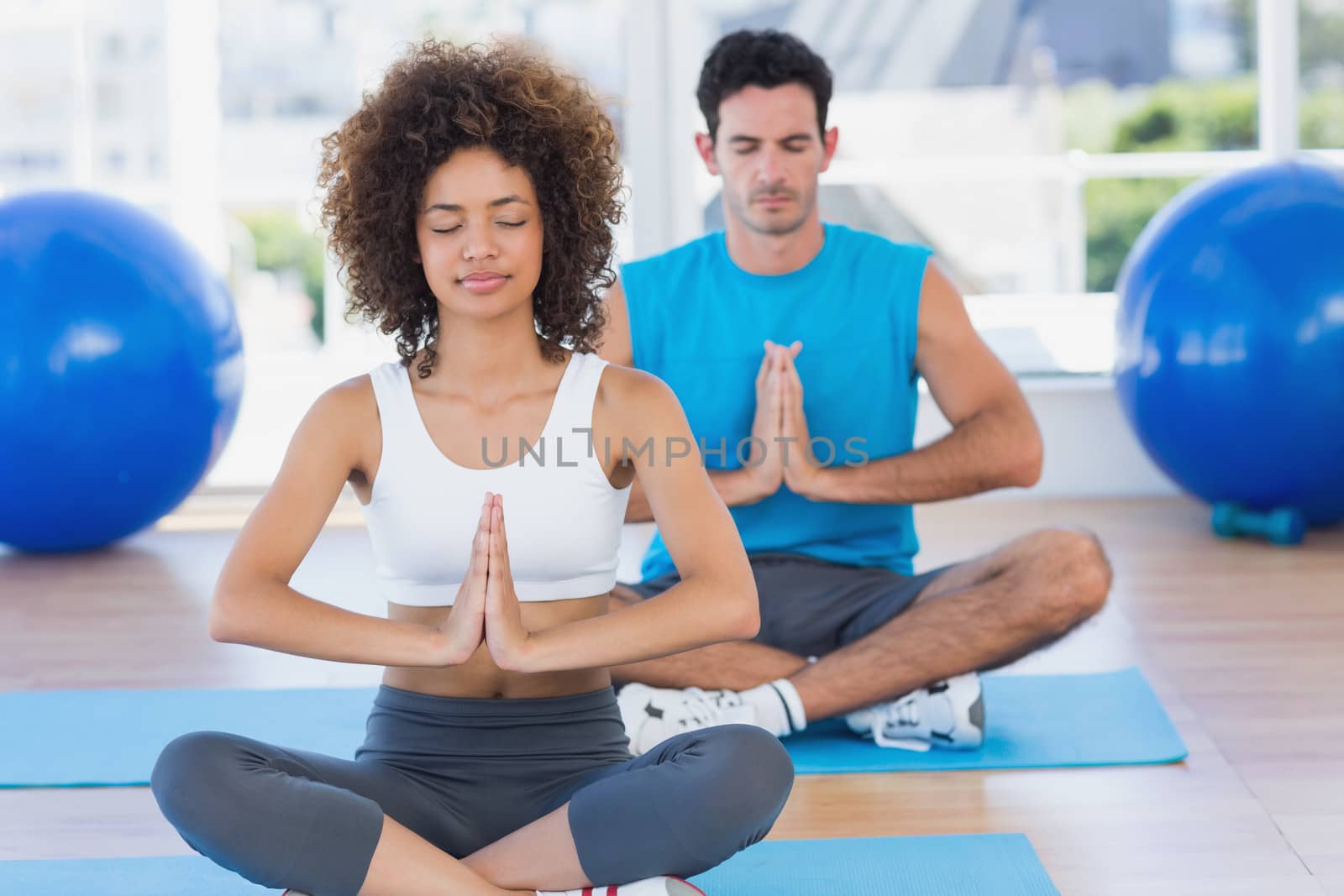 Couple with joined hands and eyes closed at fitness studio by Wavebreakmedia