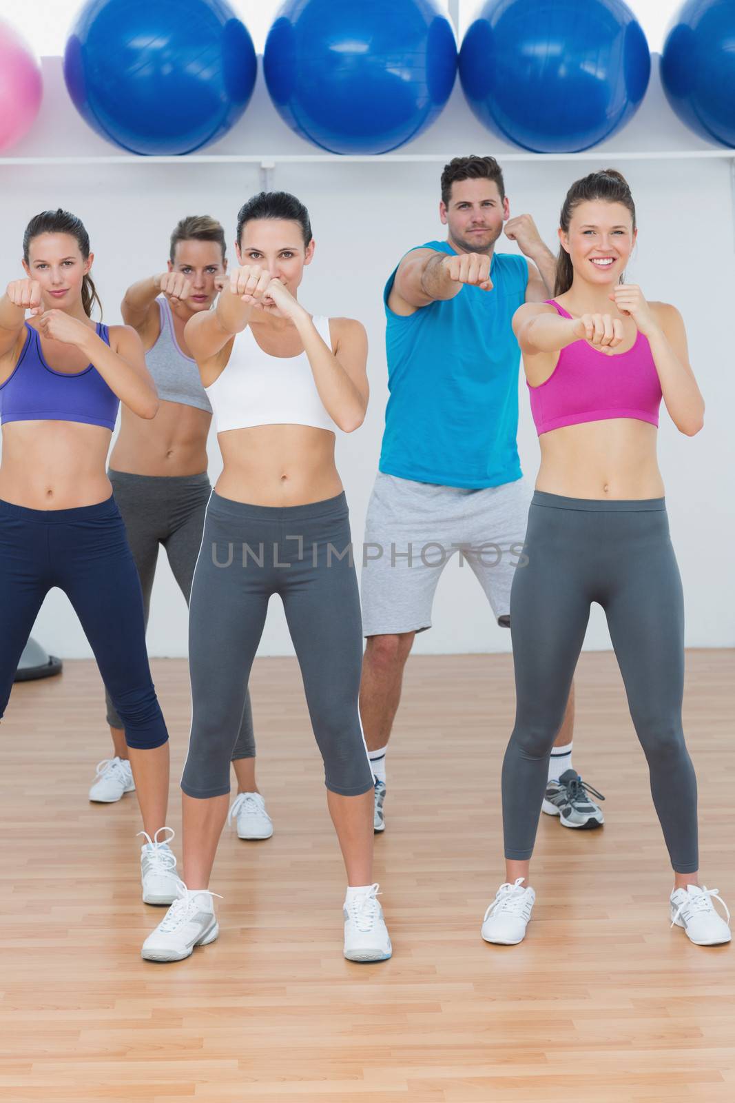 Portrait of smiling people doing power fitness exercise at yoga class in fitness studio