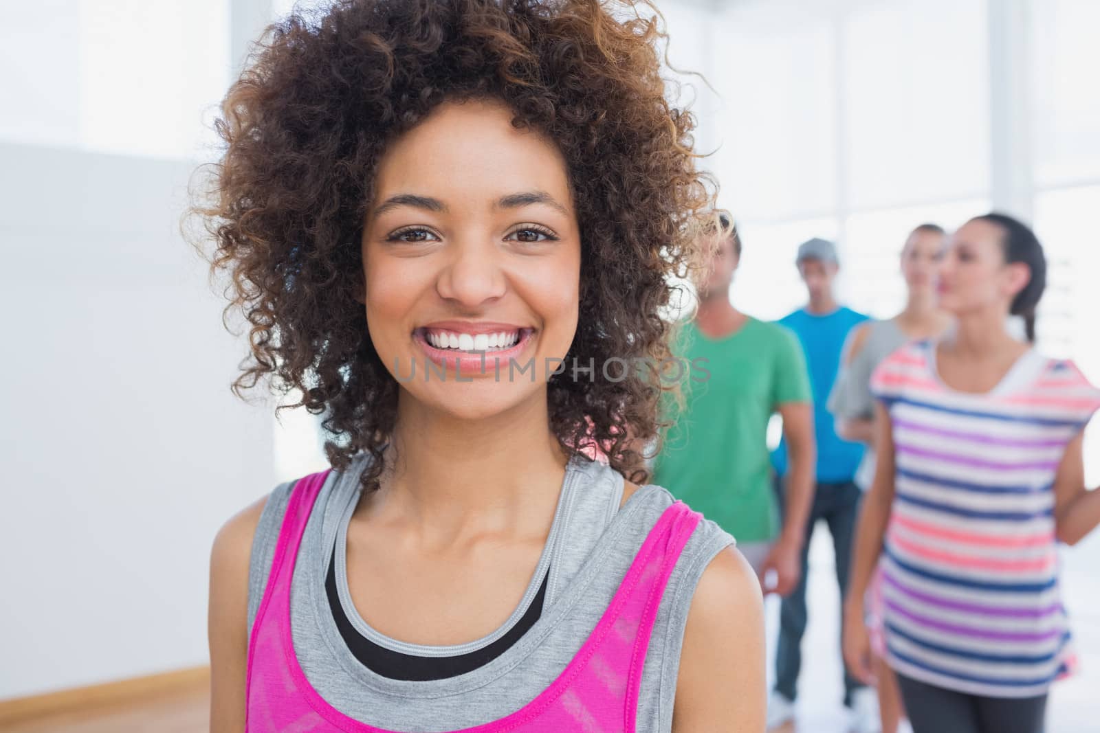 Cheerful instructor with fitness class in background by Wavebreakmedia