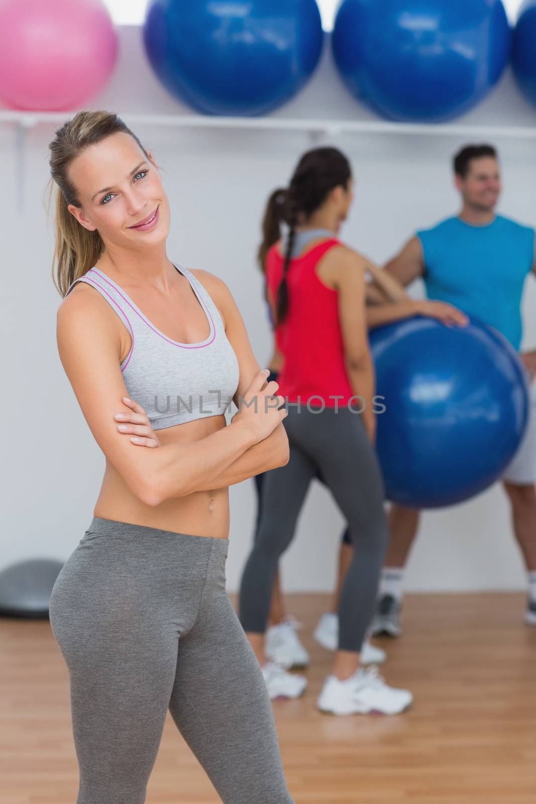 Young woman with friends in background at fitness studio by Wavebreakmedia