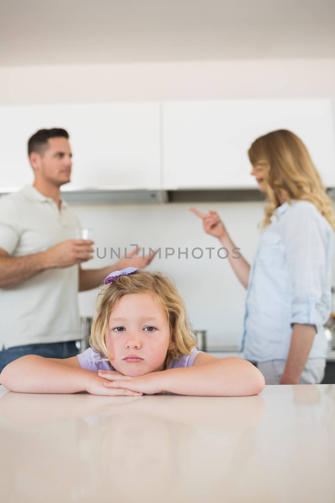 Portrait of sad girl leaning on table while parents conflicting in background at home