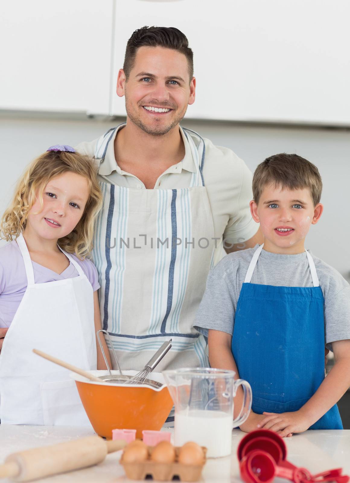Portrait of family in aprons smiling while baking cookies