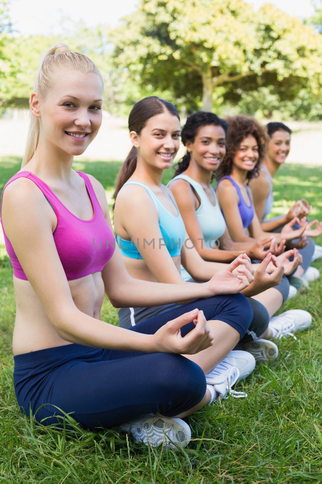 Portrait of happy female friends performing yoga exercise at park