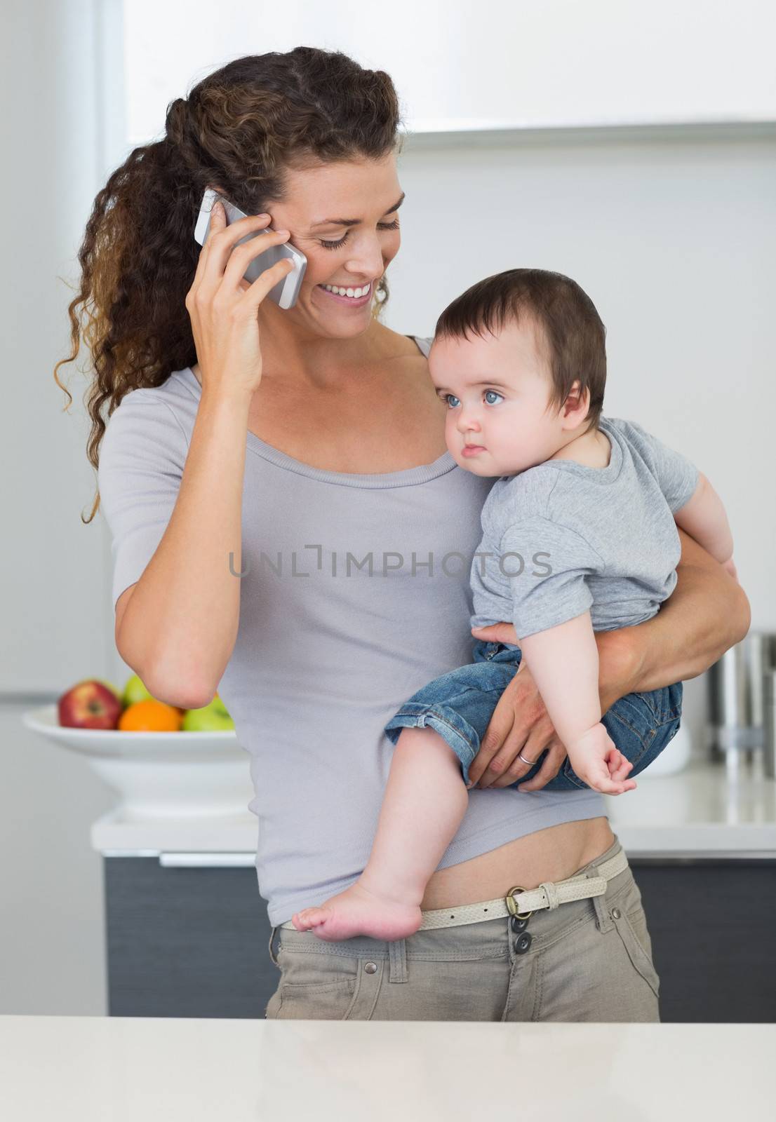 Mother using cellphone while carrying baby by Wavebreakmedia