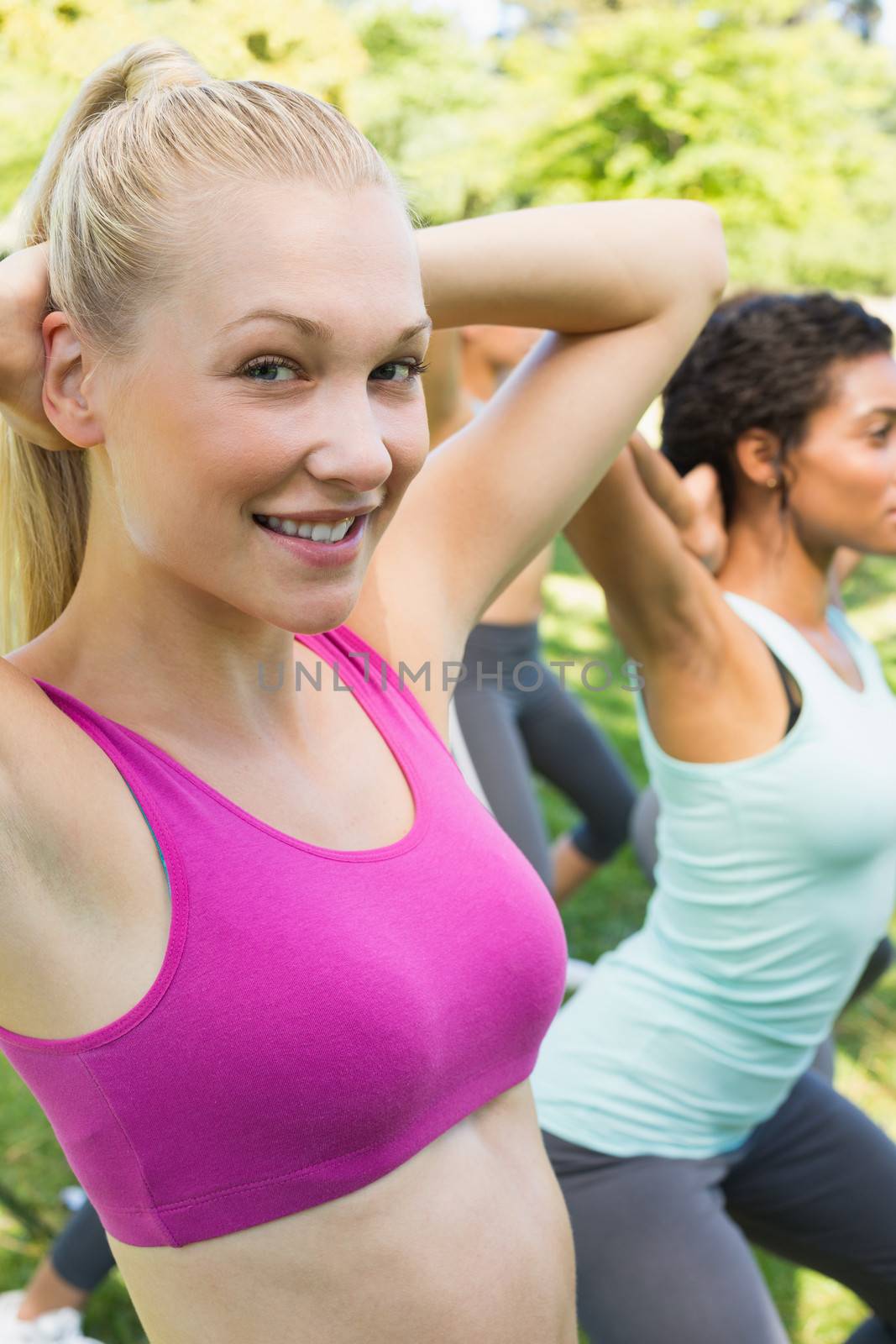 Portrait of beautiful woman exercising with friends in park