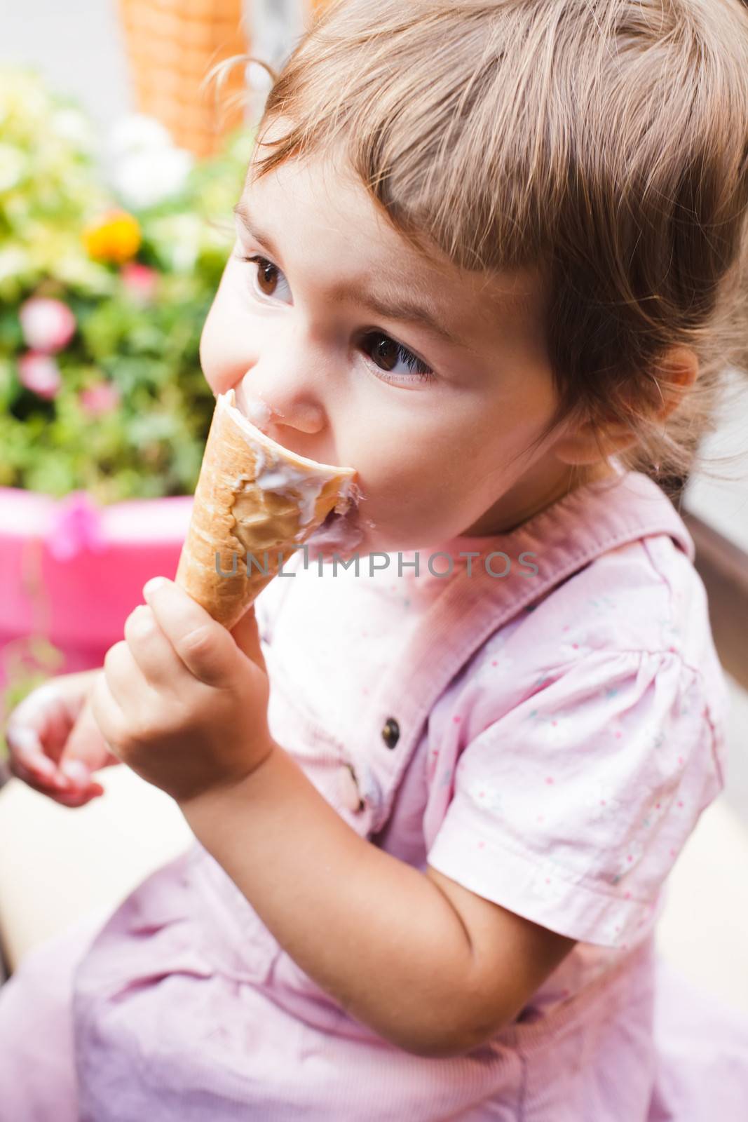 Loverly little girl eats an ice cream in cafe outdoor