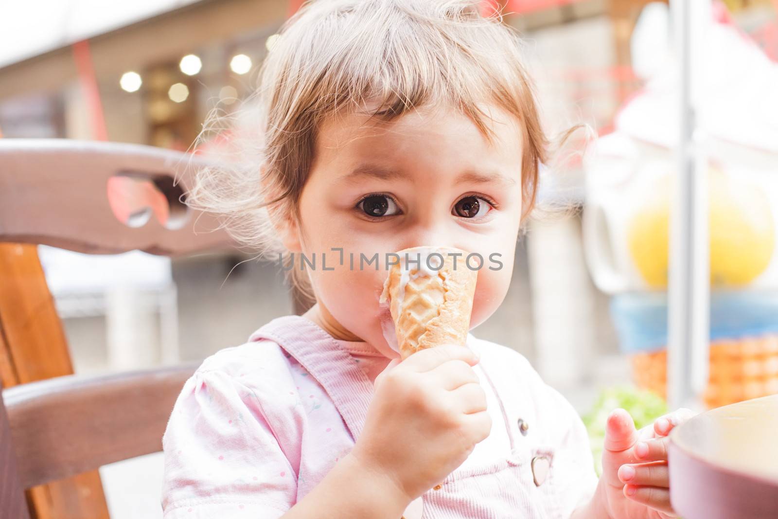 Loverly little girl eats an ice cream in cafe outdoor