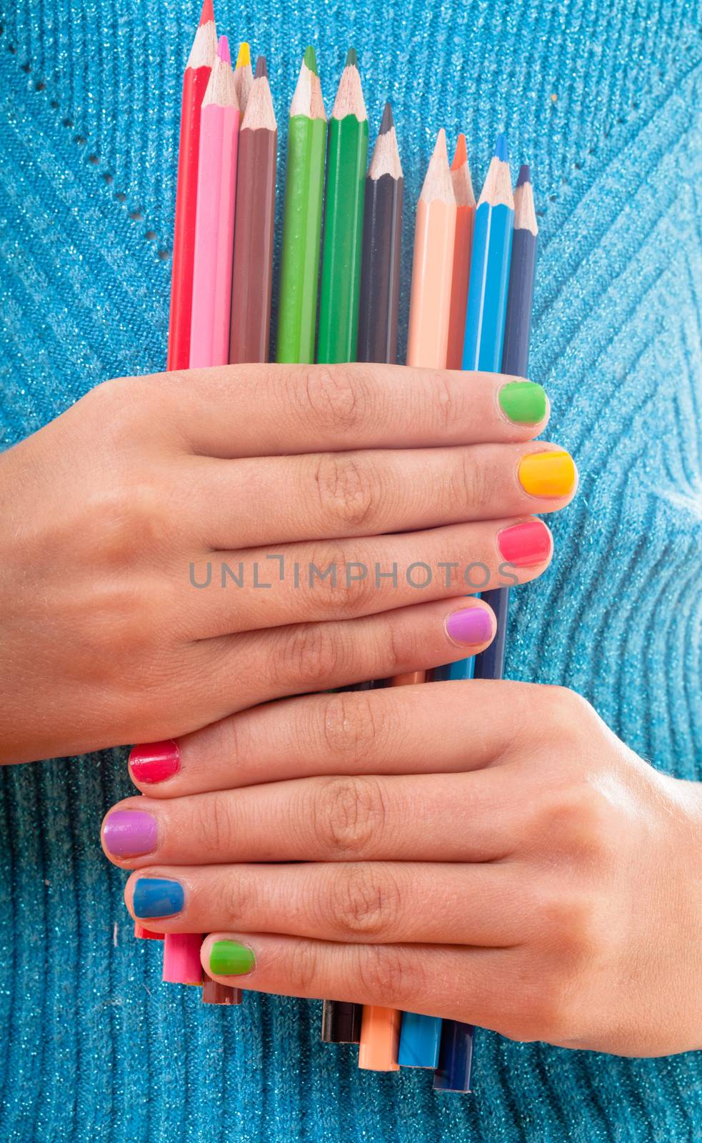 Color rainbow pencils and teenager's hands with multicoloured nails