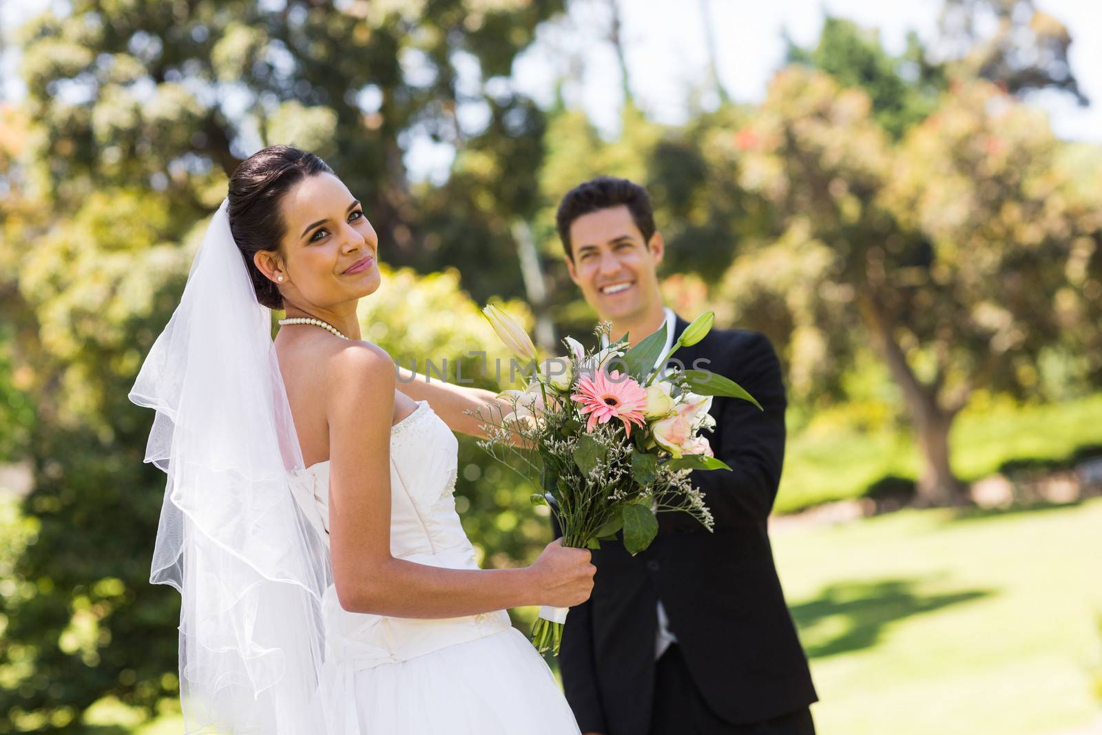 Portrait of a happy newlywed couple with bouquet in the park