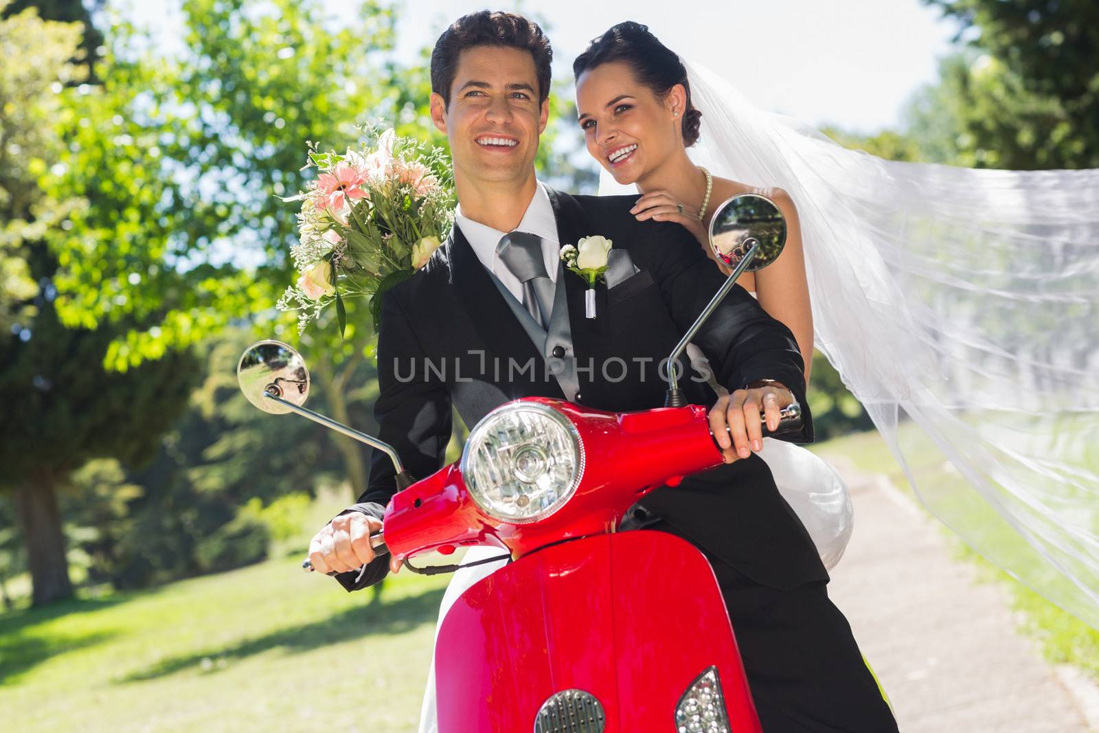 Portrait of a newlywed couple sitting on scooter in the park