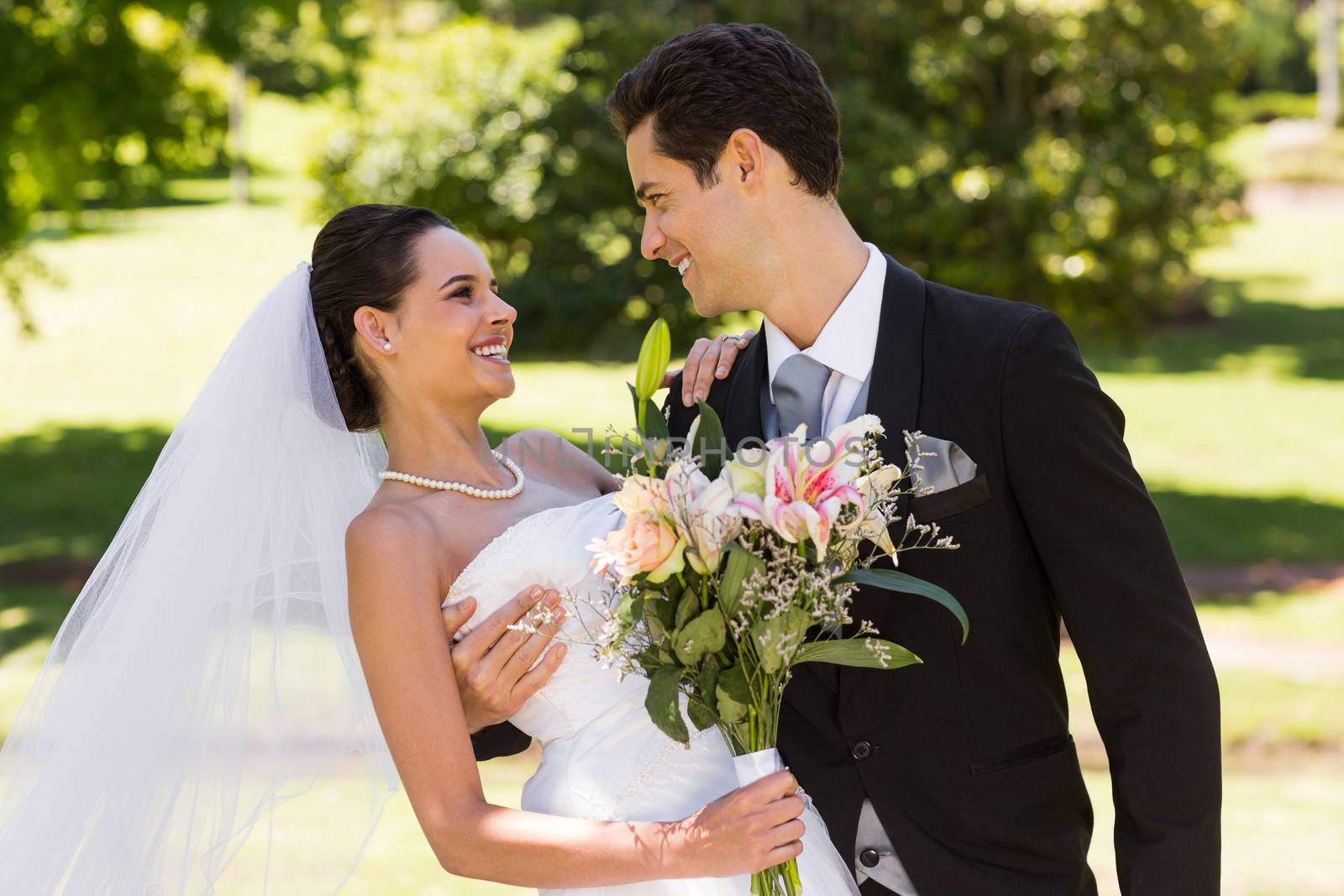 Romantic newlywed couple with bouquet in park by Wavebreakmedia