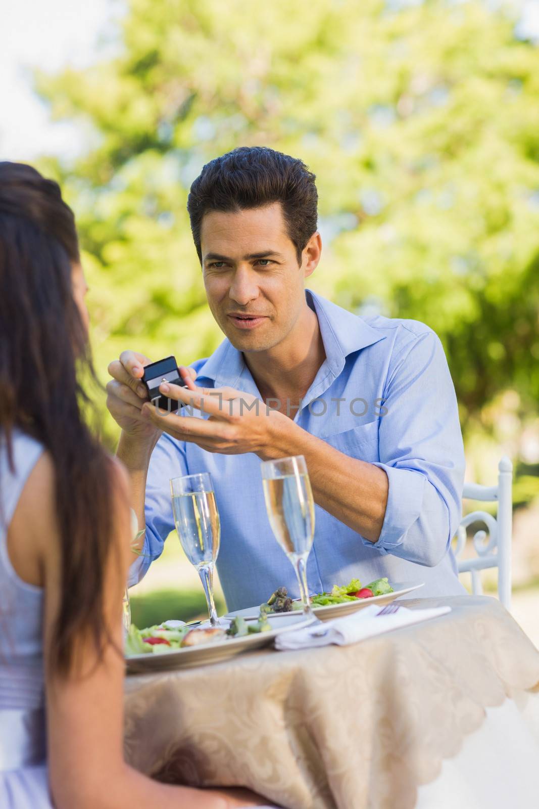 Man proposing a woman at an outdoor caf├® by Wavebreakmedia