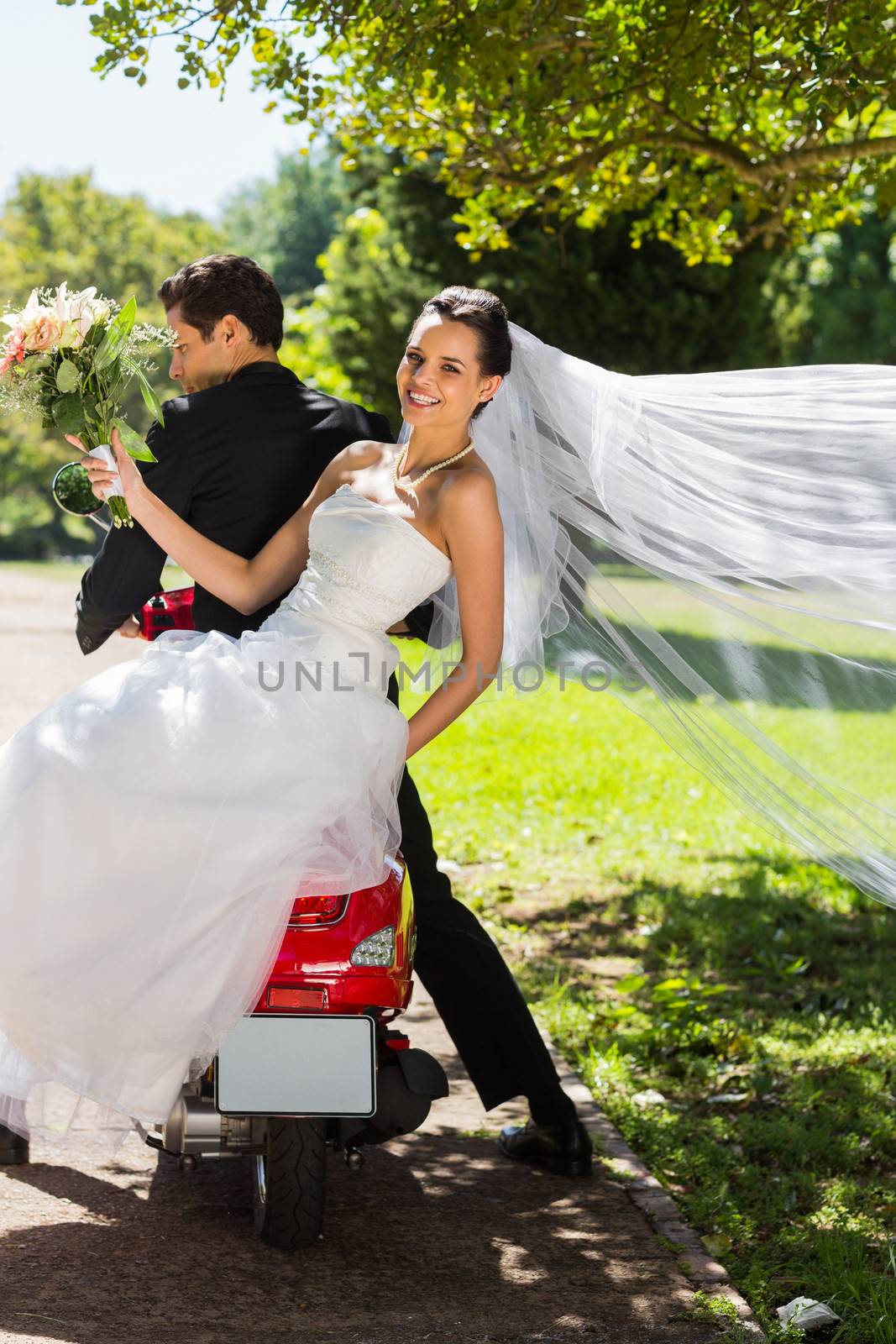 Full length of a newlywed couple sitting on scooter in the park