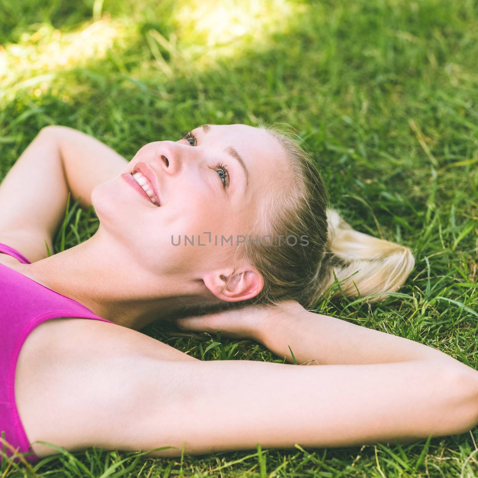 Relaxed beautiful woman lying on grass in park by Wavebreakmedia