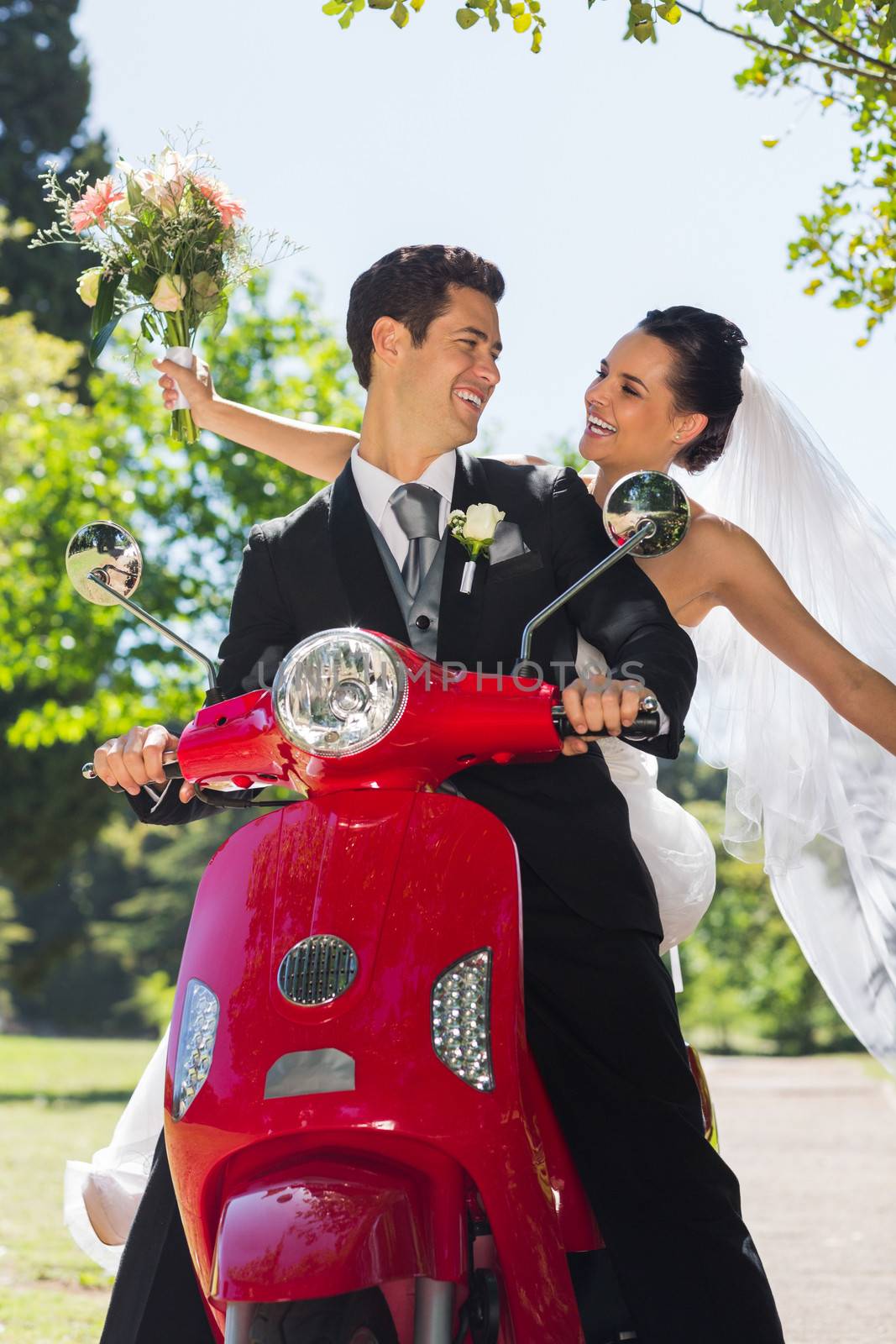 Newlywed couple sitting on scooter in park by Wavebreakmedia